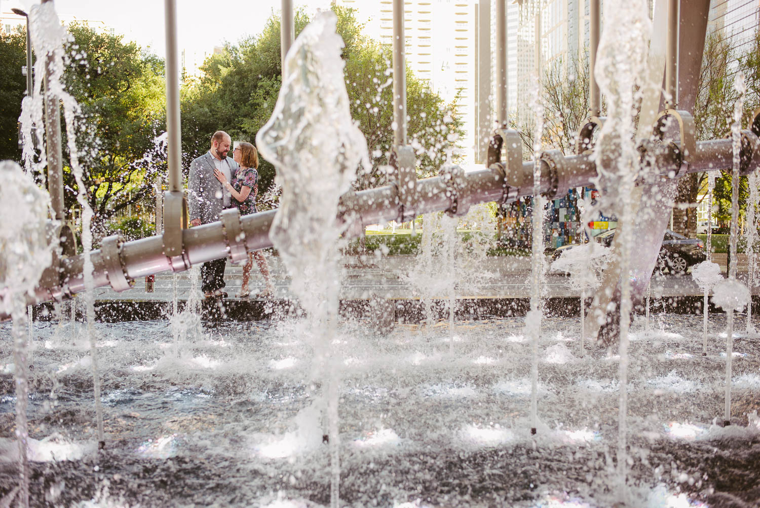 Couples engagement session at Discovery Green Houston with fountain sculpture in foreground -Philip Thomas Photography