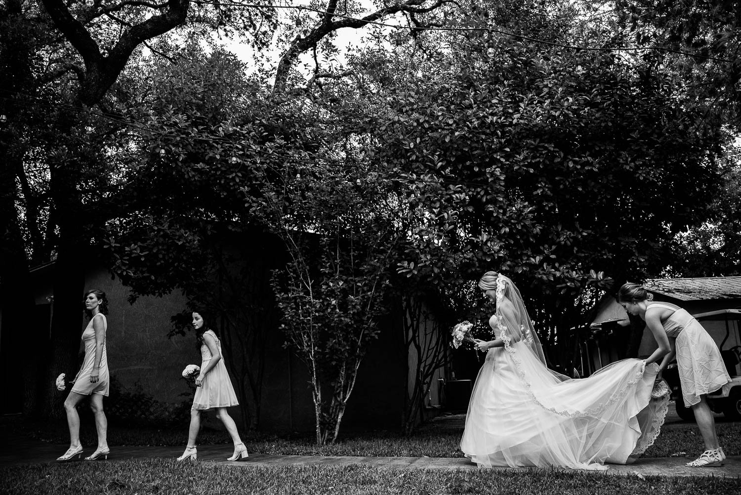 Walking out to the ceremony with bridesmaids catching brides dress The Gardens of Old Town Helotes Hill Country Wedding