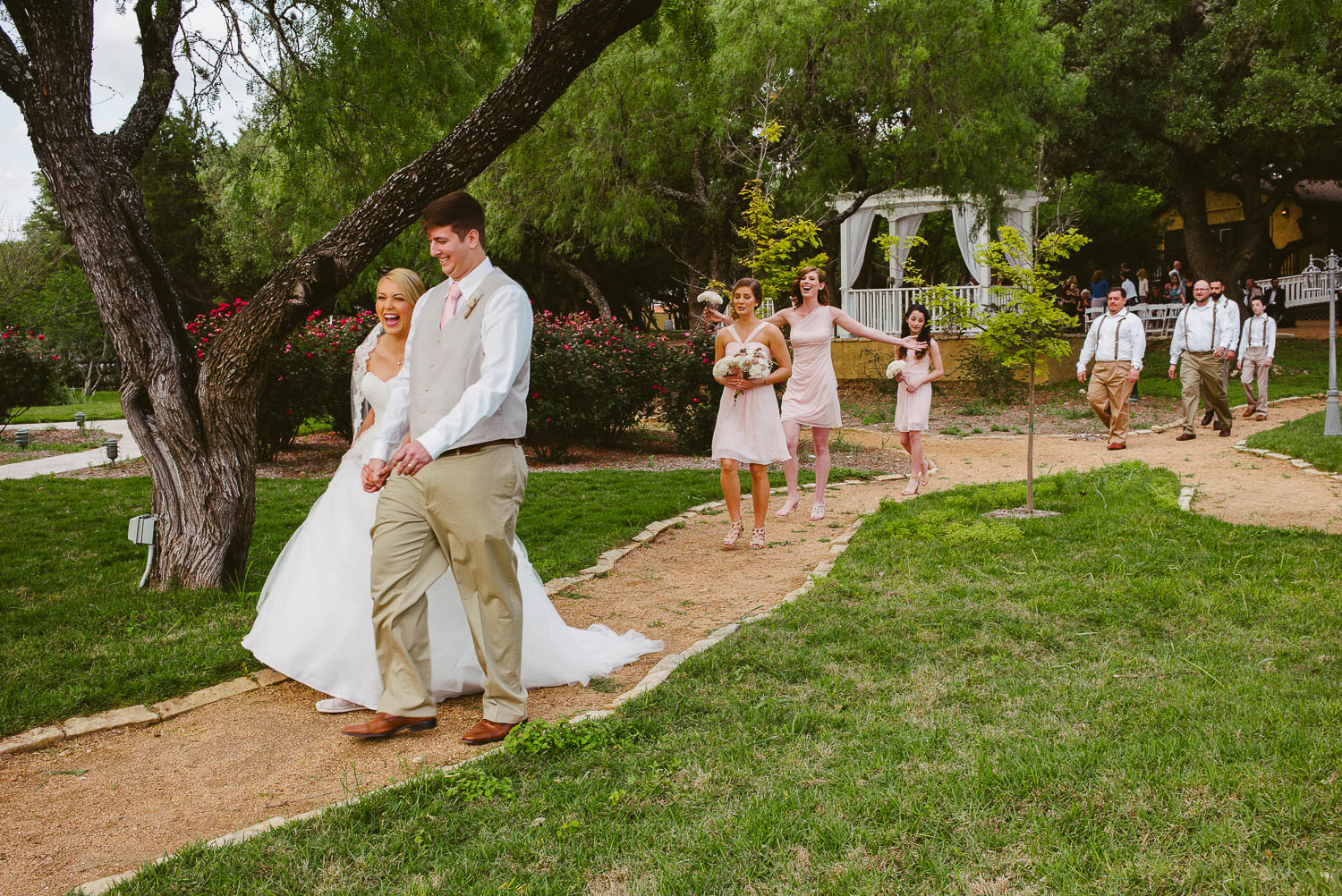 Just married couple laughing as they walk down the aisle The Gardens of Old Town Helotes Hill Country Wedding