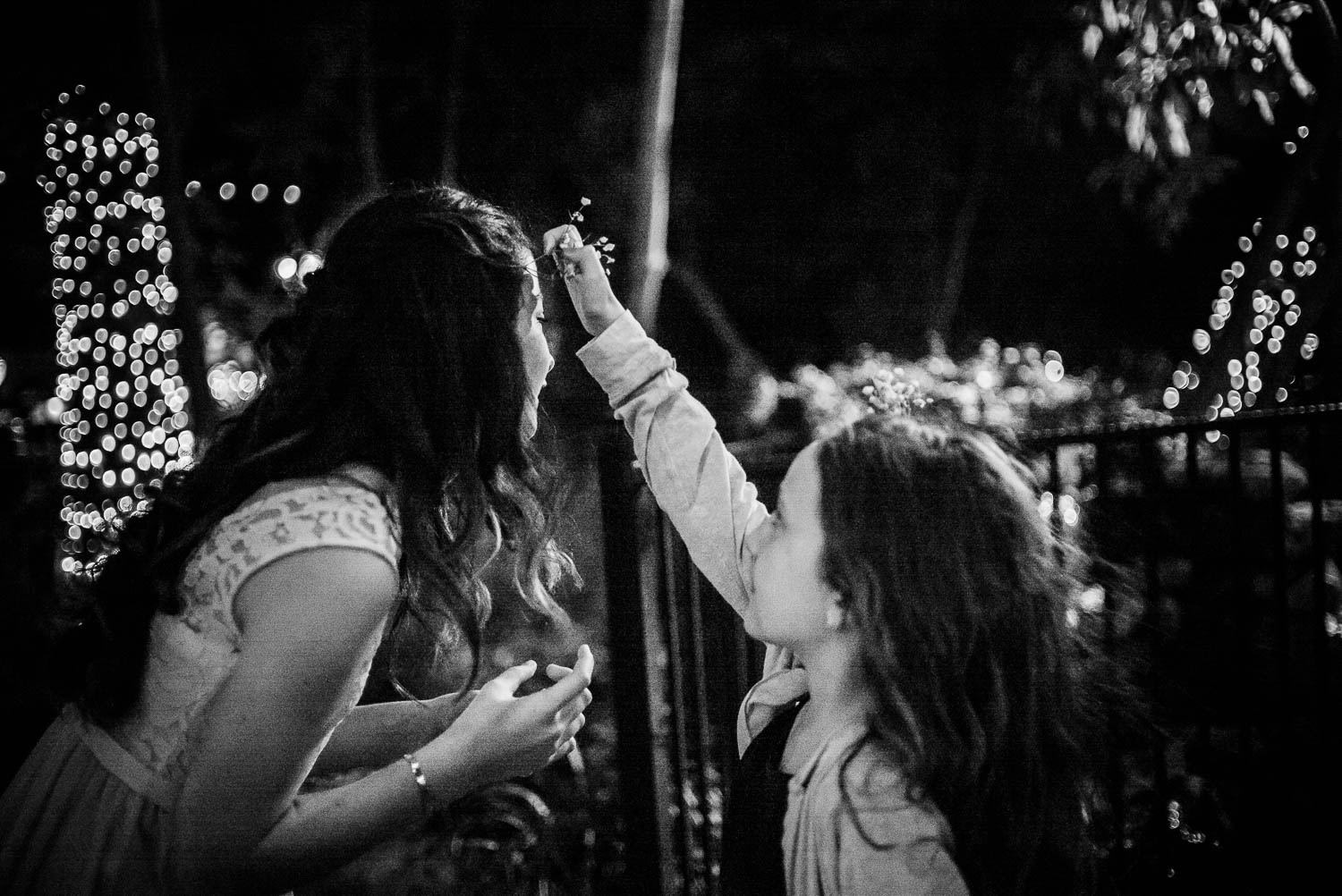 Girl places flowers in other girls hair -The Gardens of Old Town Helotes Hill Country Wedding