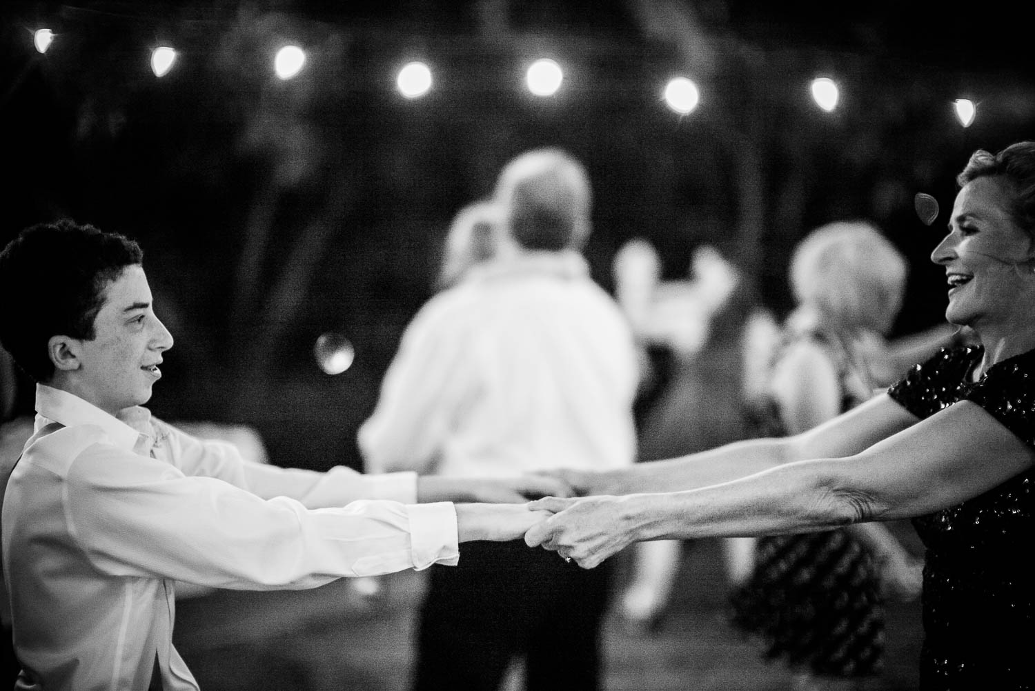 Mother and son hold hands stecthed out during the wedding reception dancing -The Gardens of Old Town Helotes Hill Country Wedding