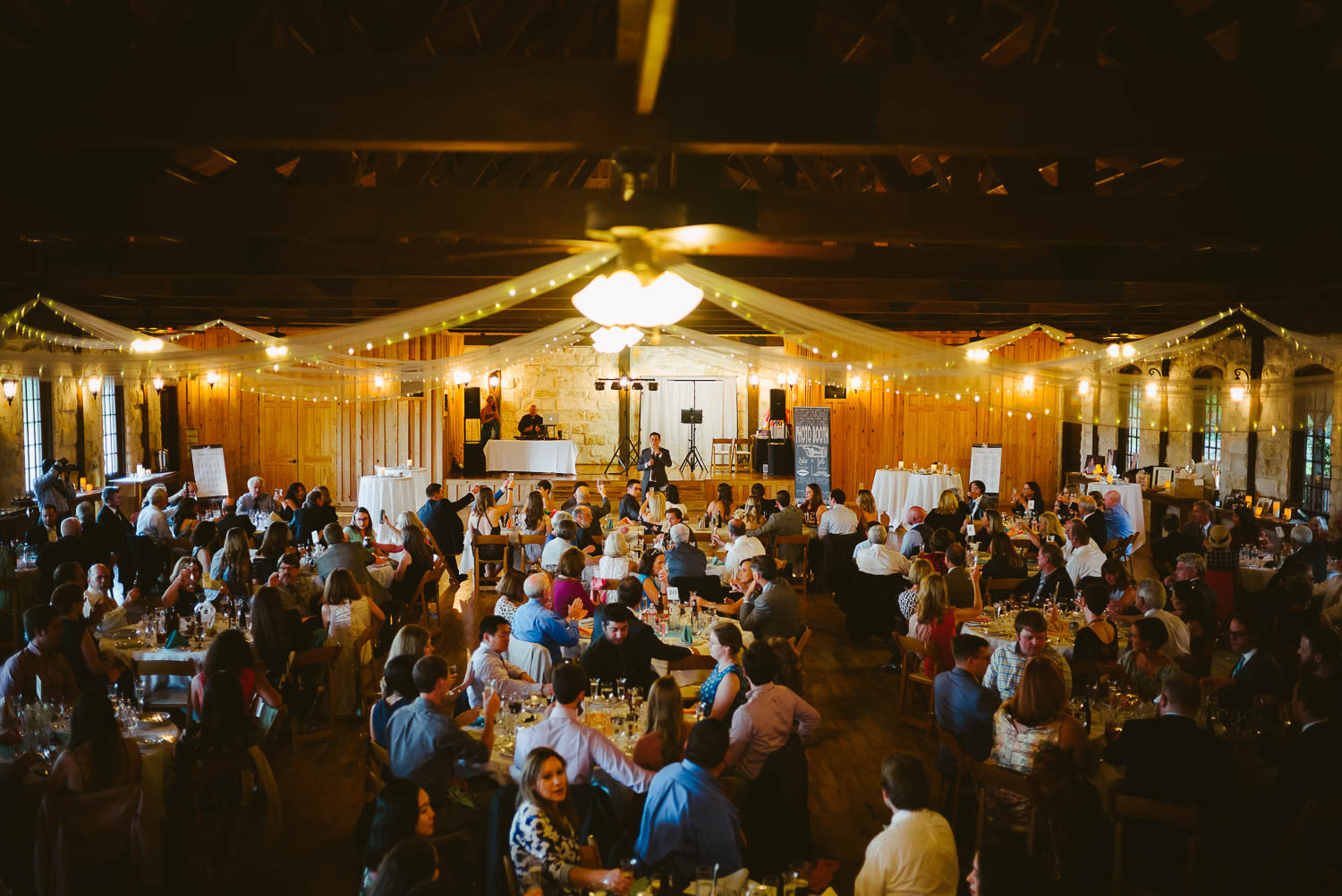 Wide angle of wedding reception with guests and father of the bride toasting Pecan Springs Houston Texas photo by Philip Thomas Photography
