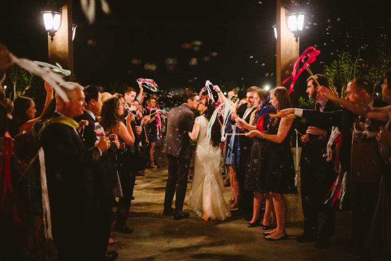 Couple momentarily stop for a kiss in front of wedding guests at they depart Pecan Springs Houston Texas photo by Philip Thomas Photography