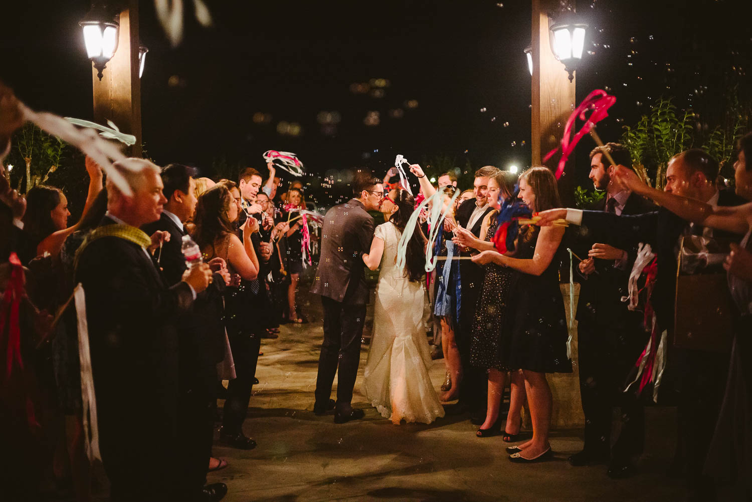 Couple momentarily stop for a kiss in front of wedding guests at they depart Pecan Springs Houston Texas photo by Philip Thomas Photography