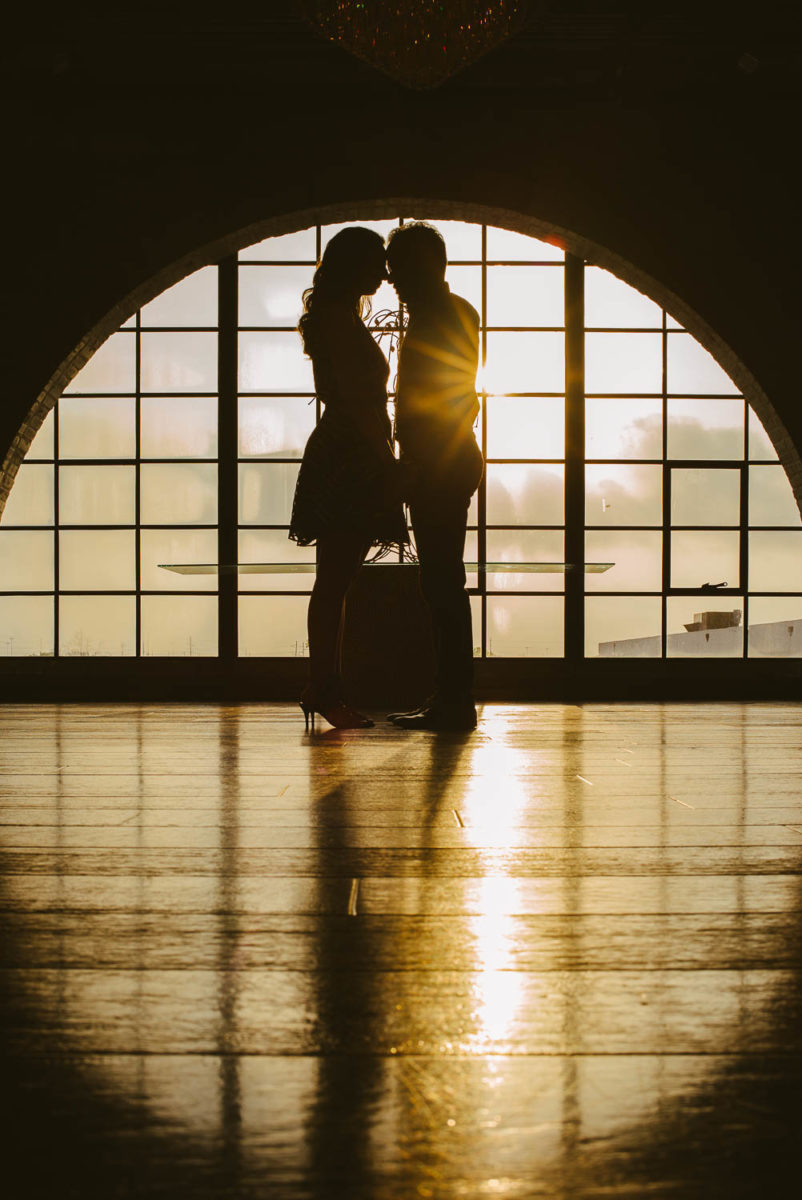 Couple lock eyes head to head at The Astorian in art deco window the Astorian Houston Texas