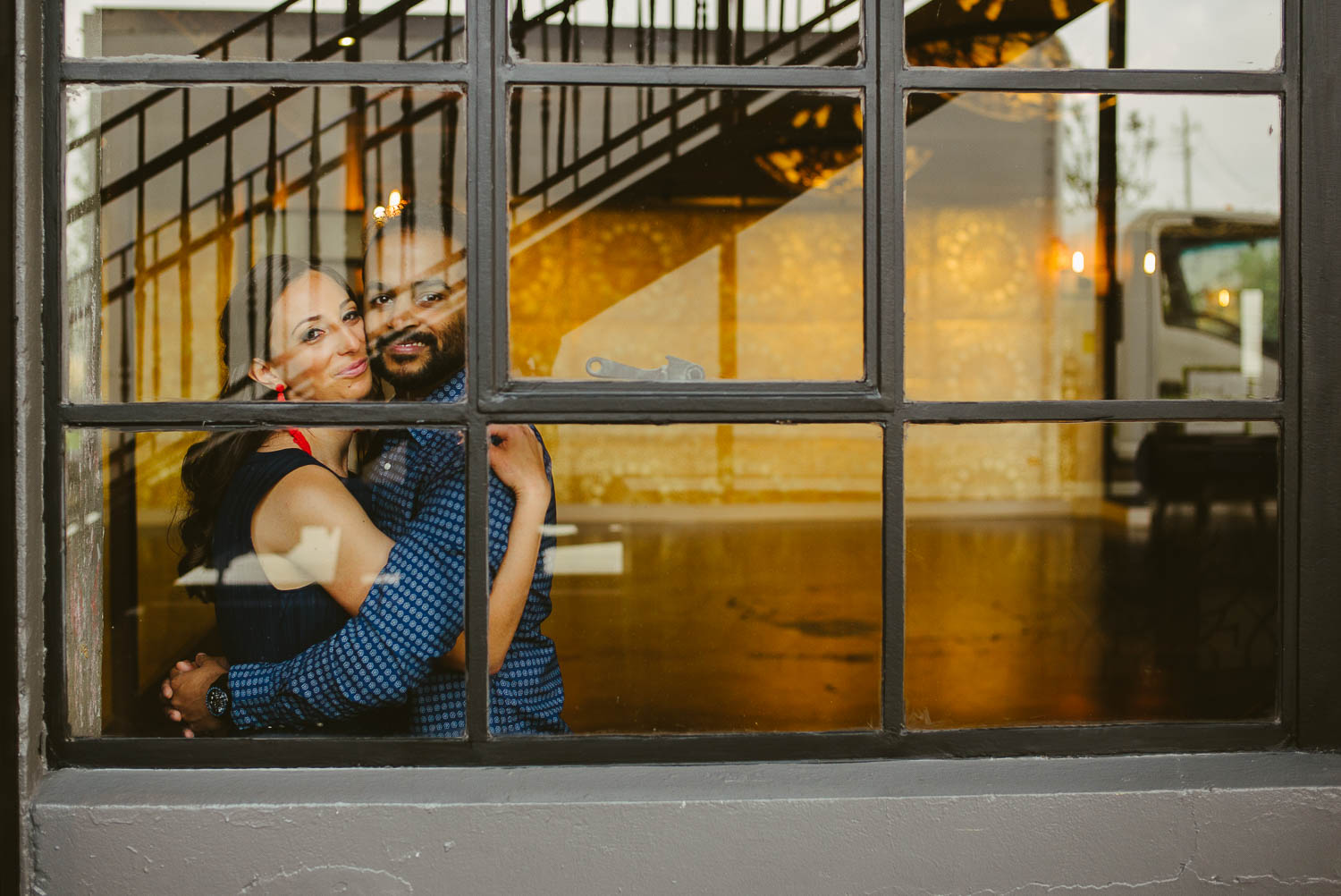 Couple look through window with reflections at The Astorian Houston Texas