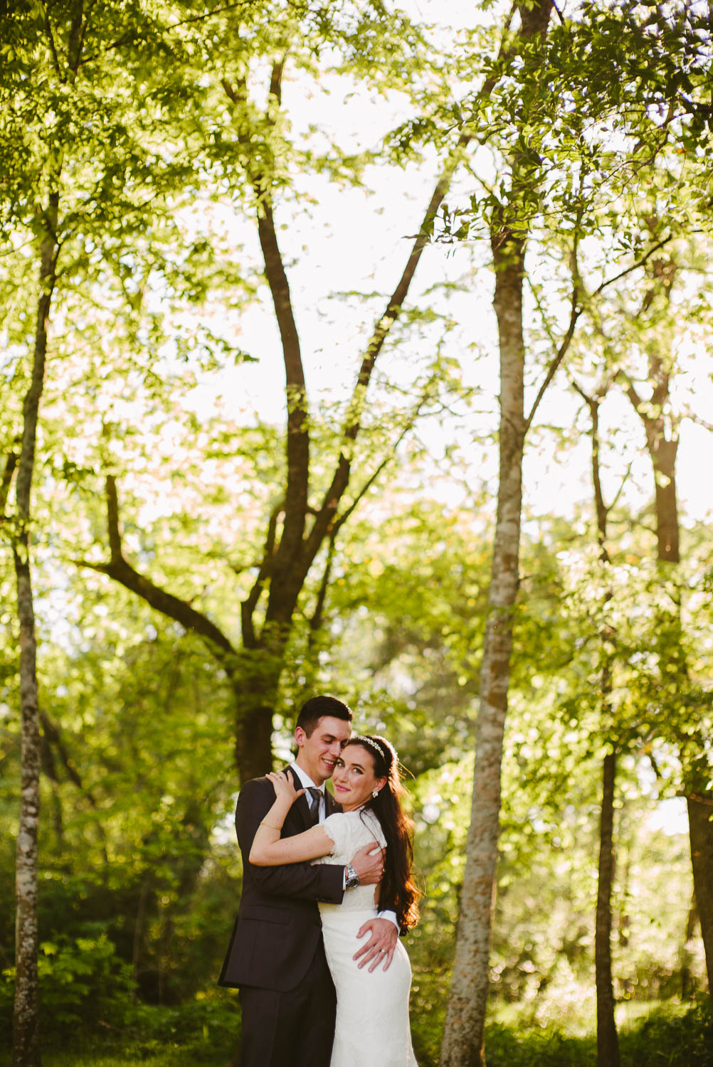Couple Bri and Max hug in a posed image with high trees at Pecan Springs Houston Texas photo by Philip Thomas Photography