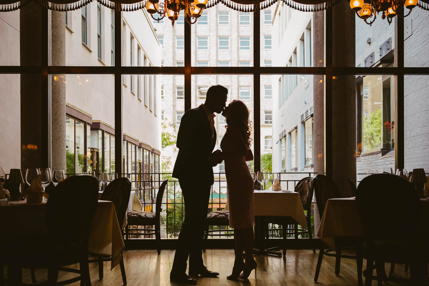 Couple kiss silhouetted against San Antonio city Houston Street engagement shoot