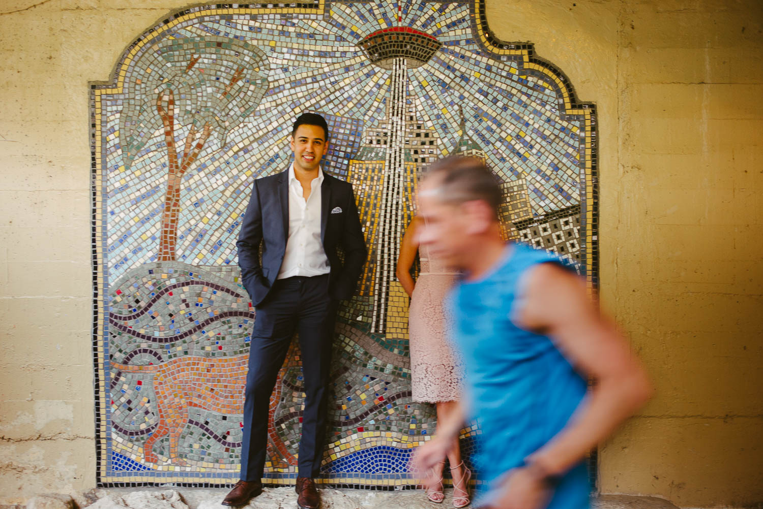 Couple posing for engagement shoot as runner runs through shot along the riverwalk San Antonio Texas