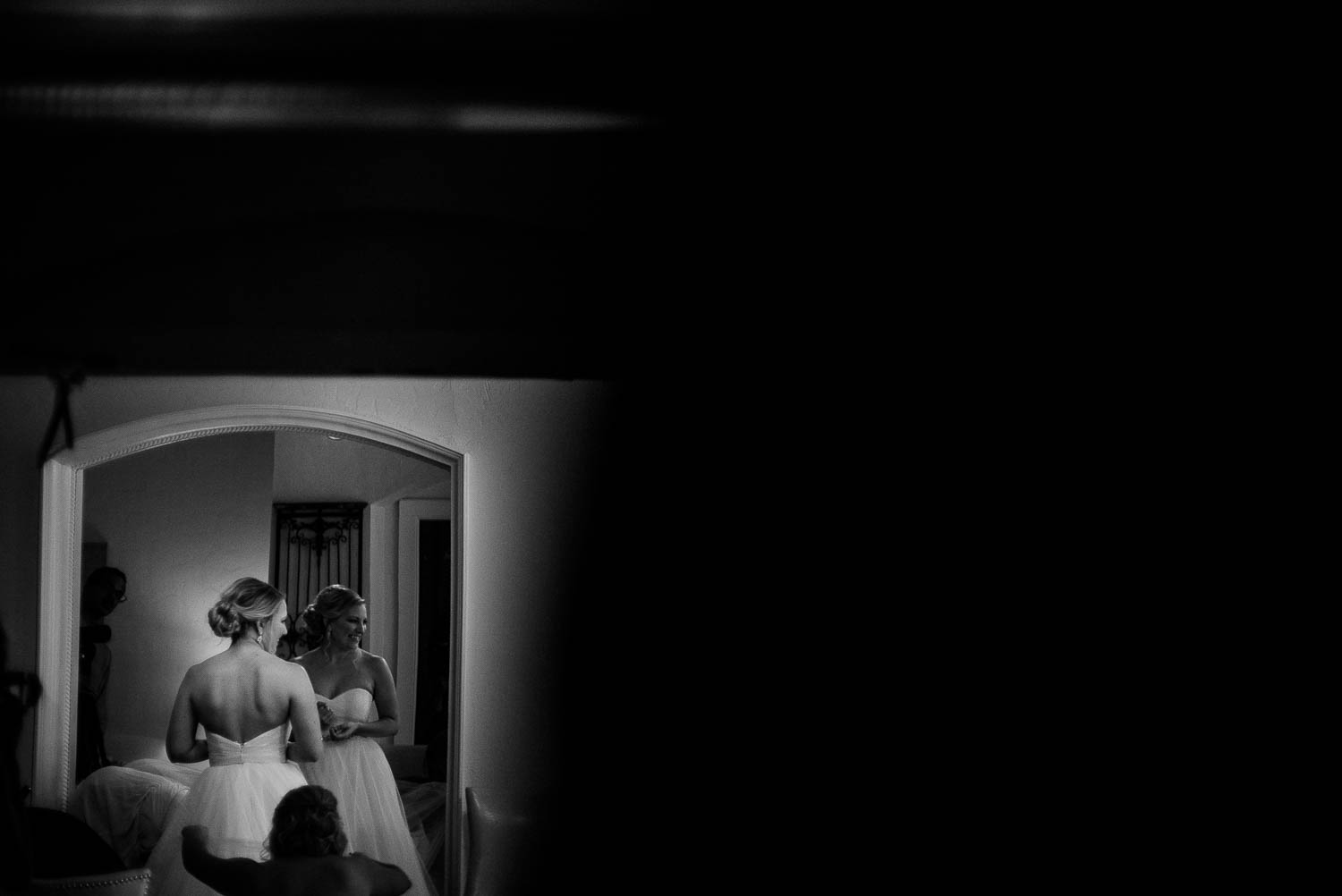 Dar against light shows the bride checking herself in a large mirror at the Bell Tower on 34th Houston-Leica wedding photographer-Philip Thomas Photography