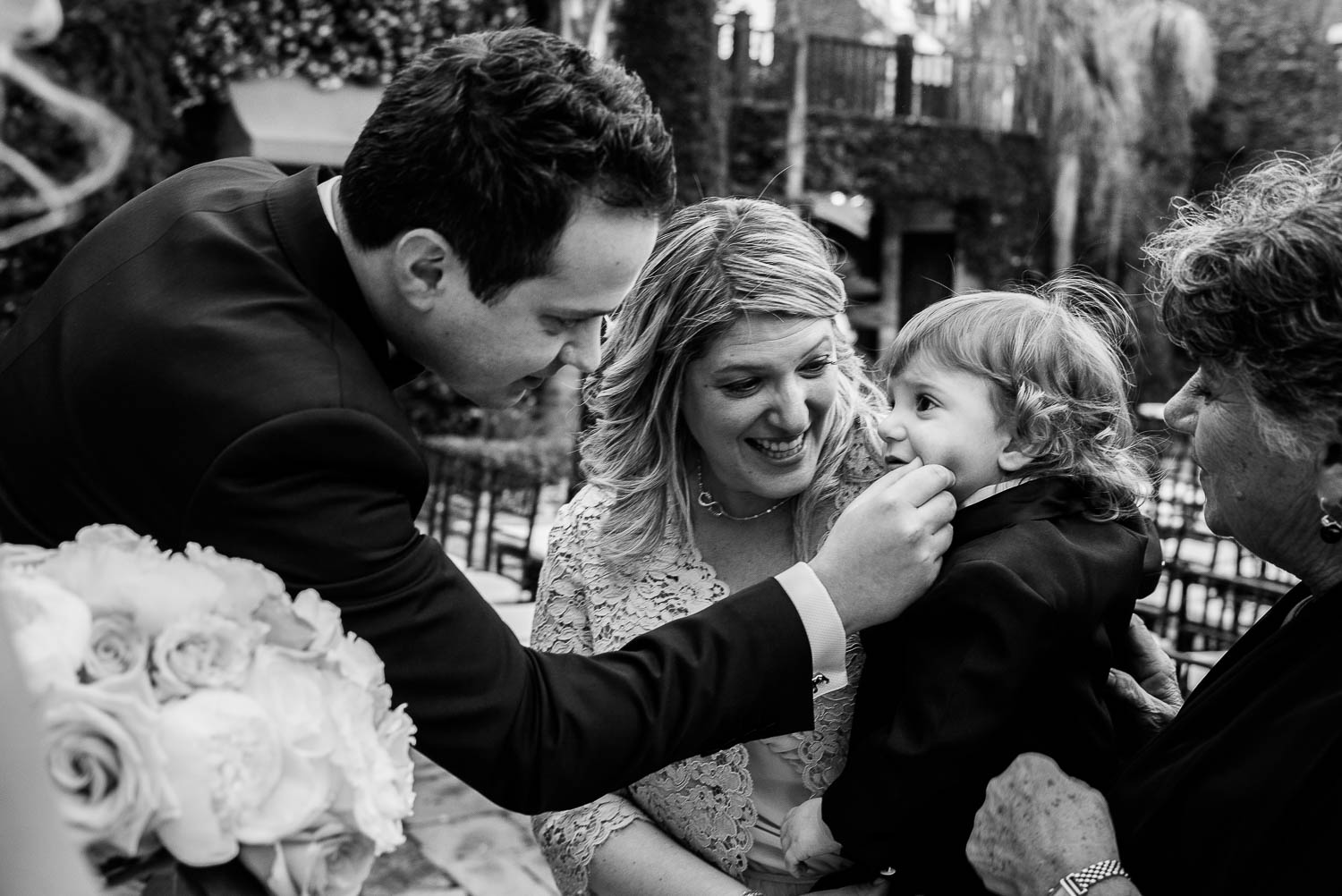 Bride and groom chat and squeeze little boys cheek at a wedding cocktail party Bell Tower on 34th Houston-Leica wedding photographer-Philip Thomas Photography