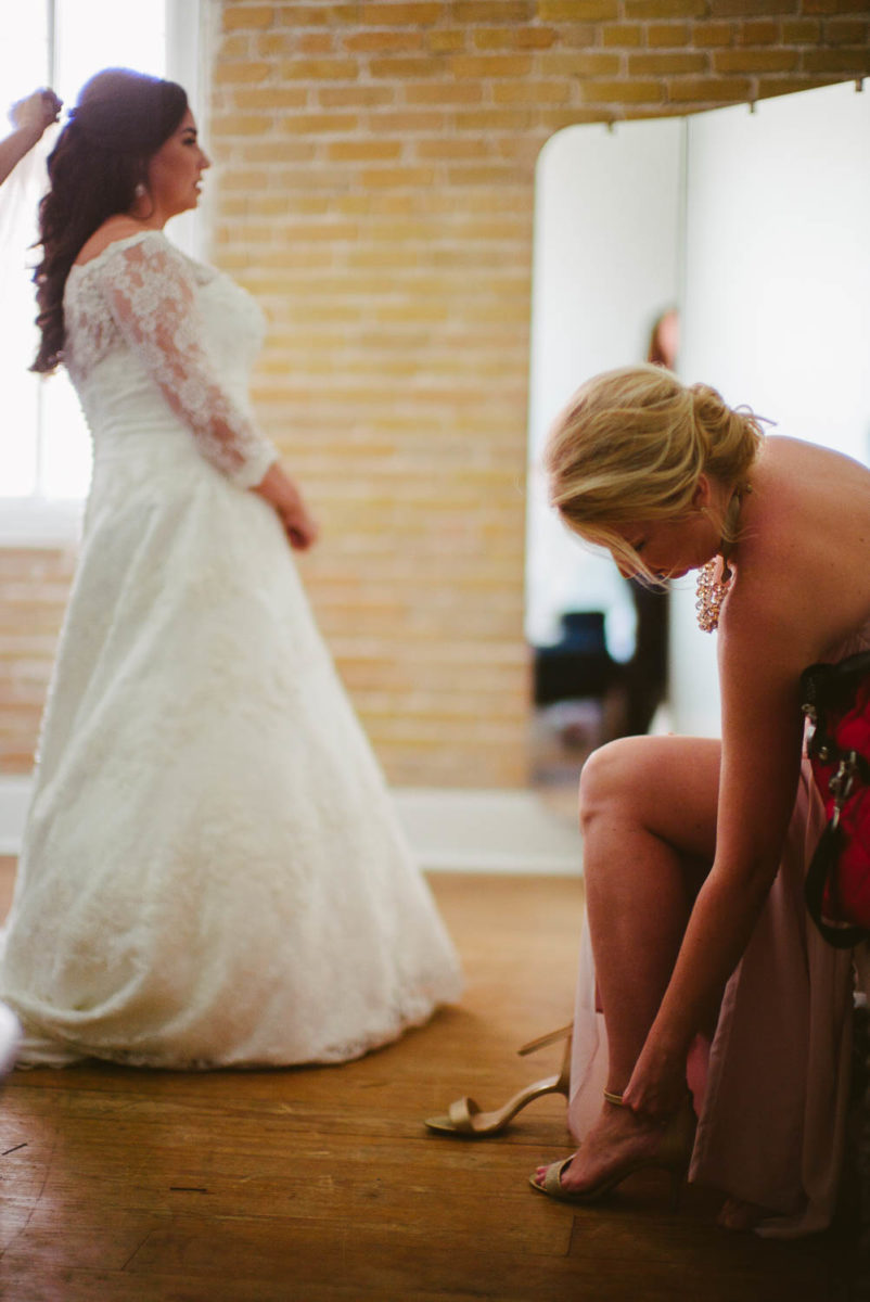 Bride has veil fitted as friend fits a shoe Za Za gardens-Leica photographer-Philip Thomas Photography