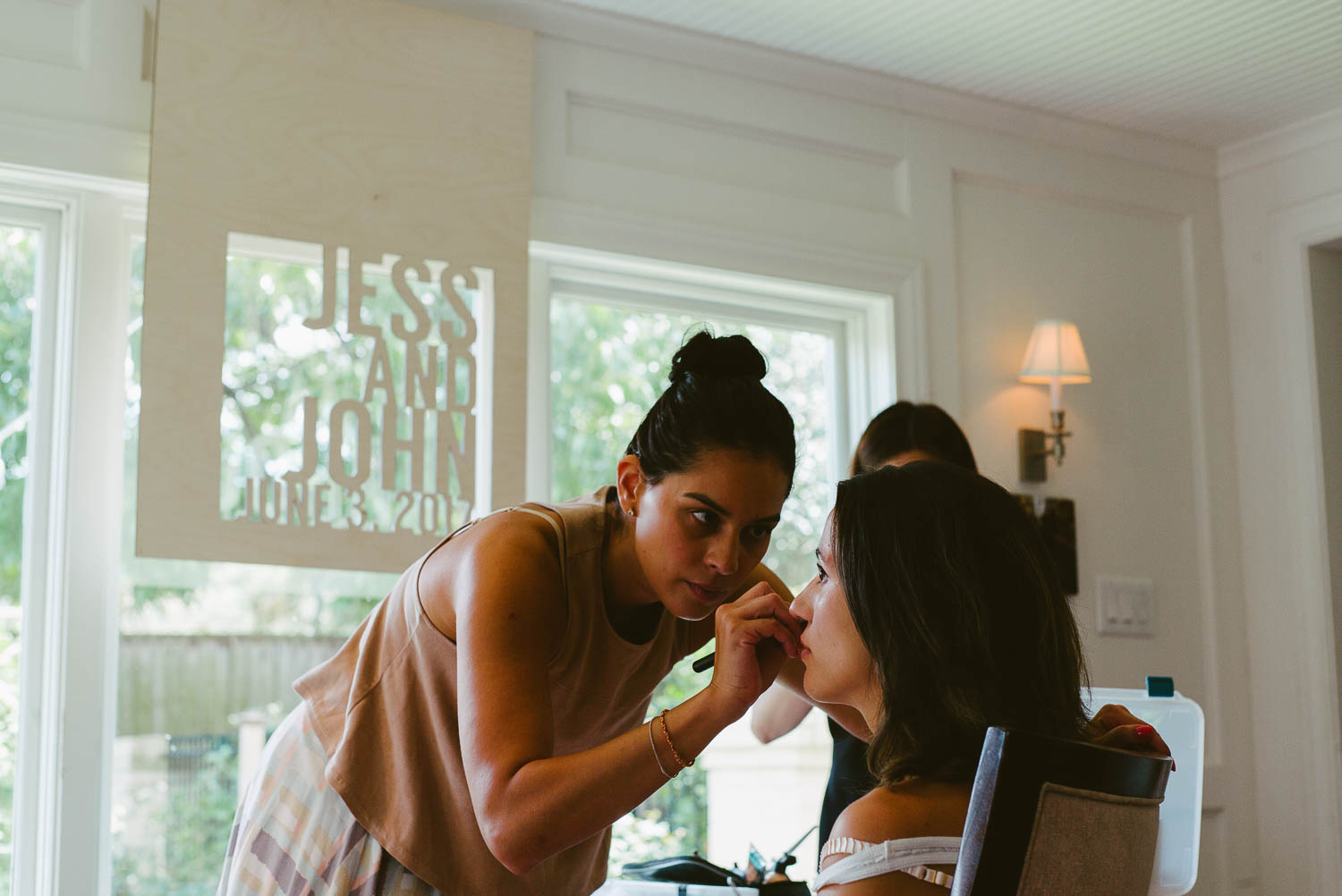 Hair and makeup is applied to the bride Jessica on her wedding day. Behind them are the cut outs Jess and John-Leica photographer-Philip Thomas Photography