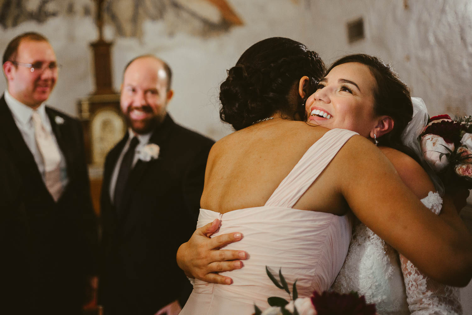 We did it as bride hugs cousin and groom looks back toward his bride at Mission Concepcion Wedding-Leica photographer-Philip Thomas Photography