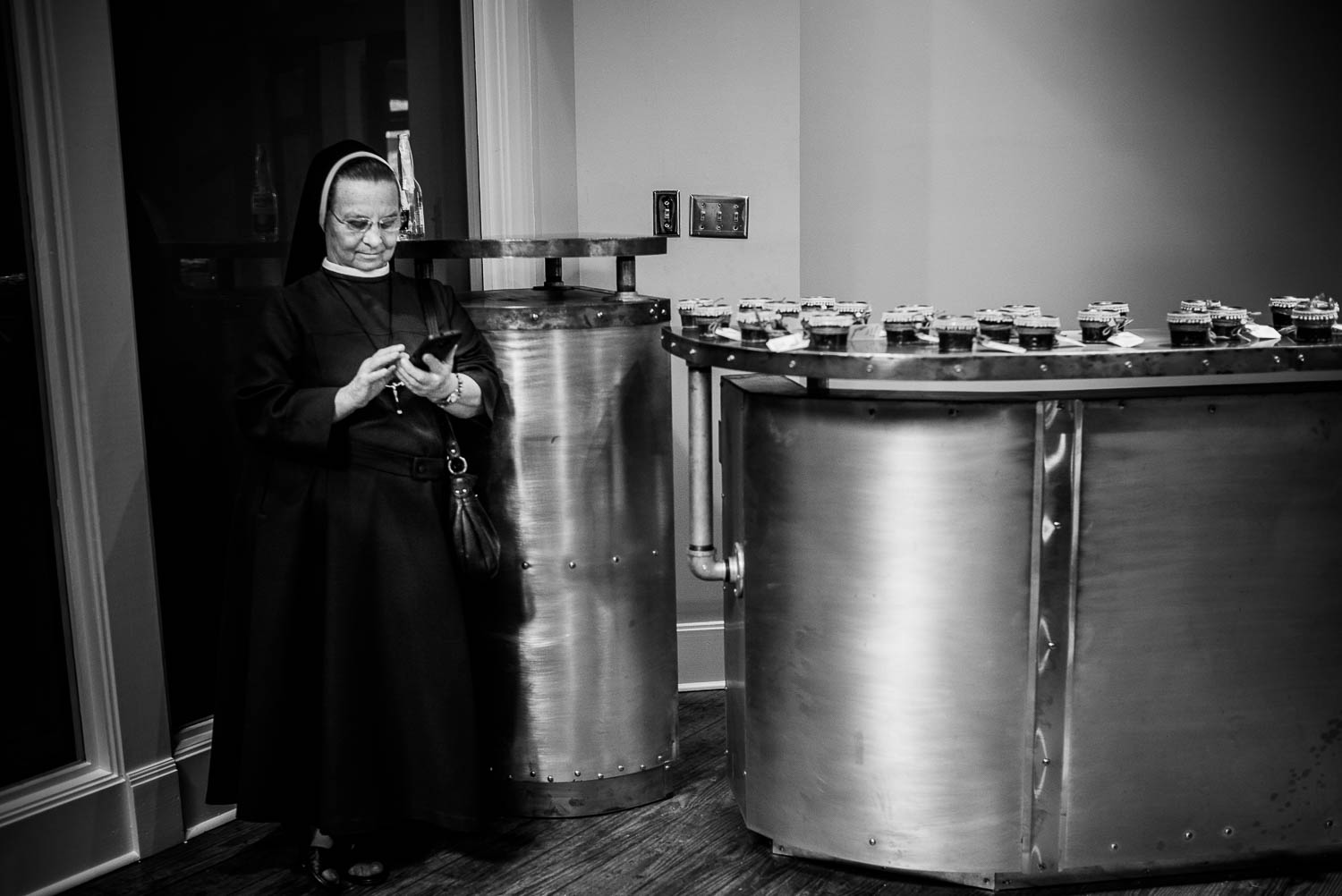 A nun scrolls her phone near some desserts at Za Za Gardens Wedding Reception-Leica photographer-Philip Thomas Photography