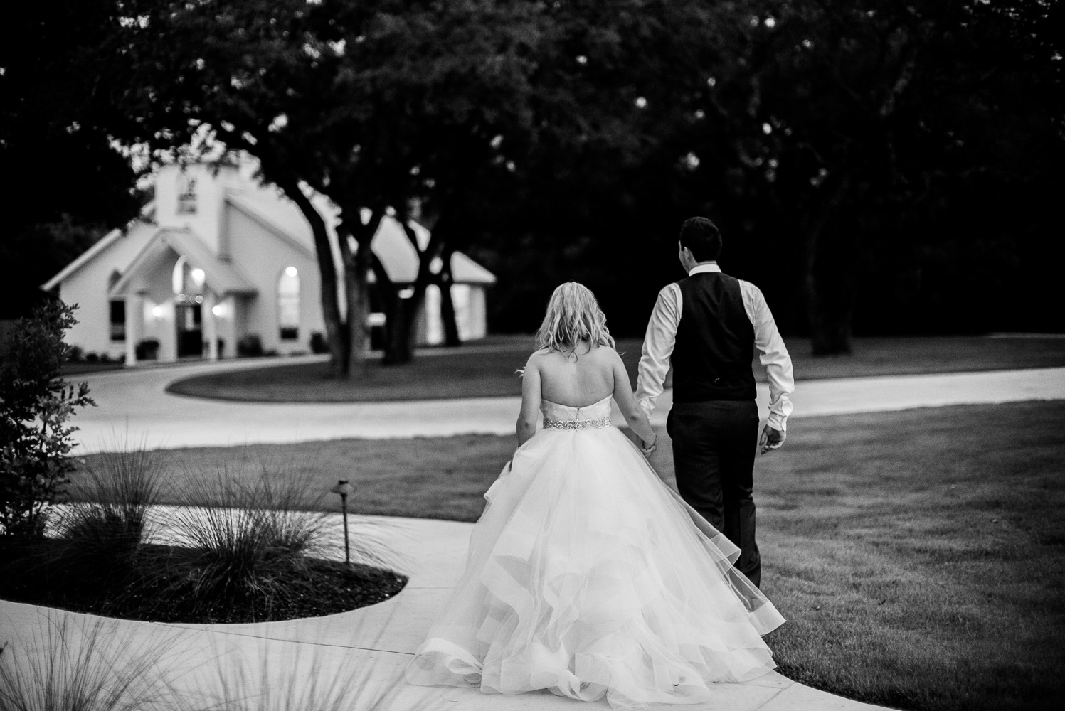 Wedded couple walk holding hands at Chandelier of Gruene Wedding Reception-52