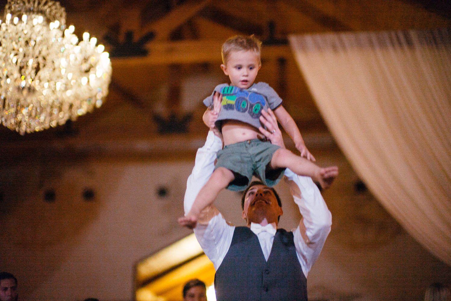 Groom lifts up ring bearer to the ceiling at Chandelier of Gruene Wedding Reception-60