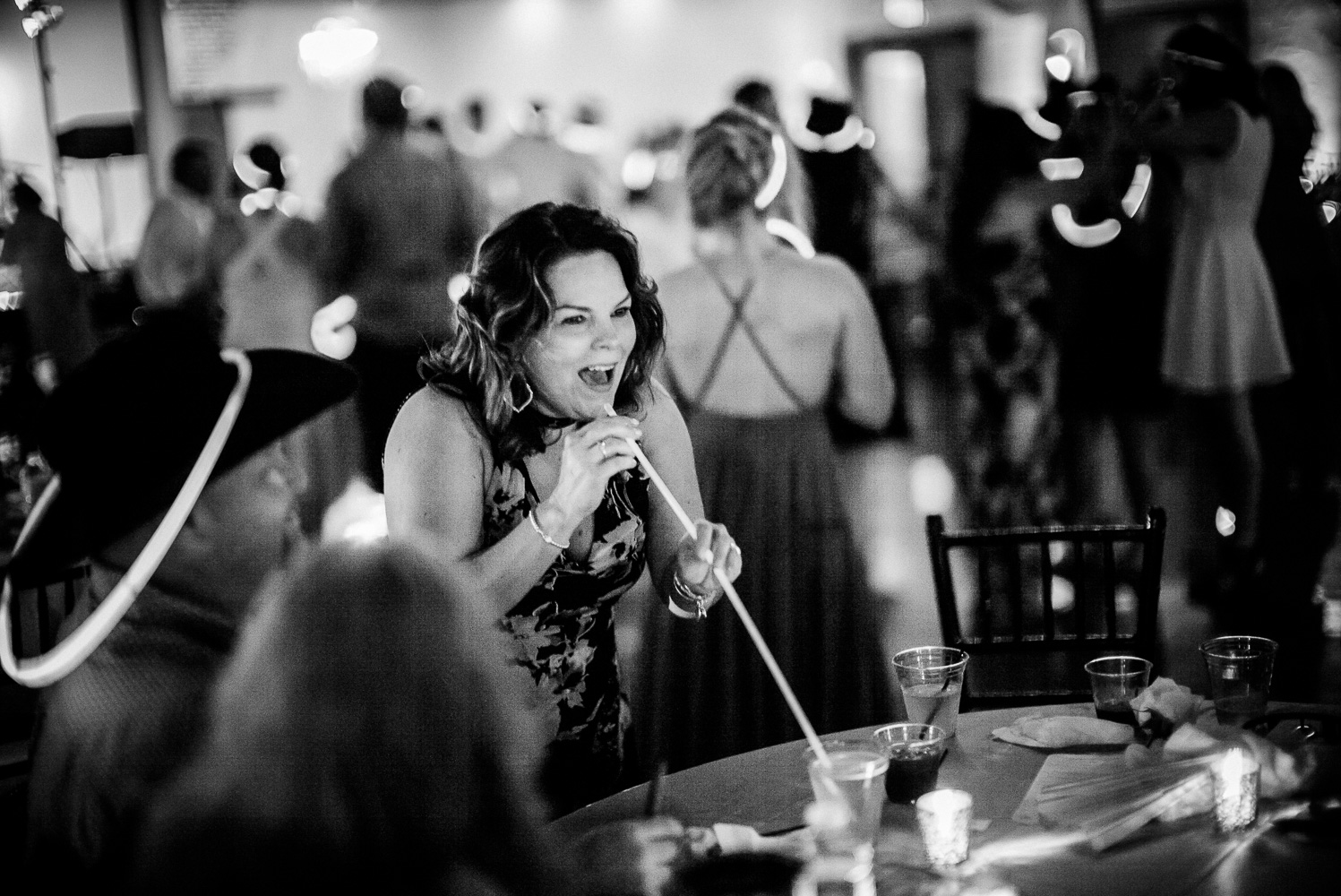 Guest pretends to sip a drink from a light wand Chandelier of Gruene Wedding Reception-66