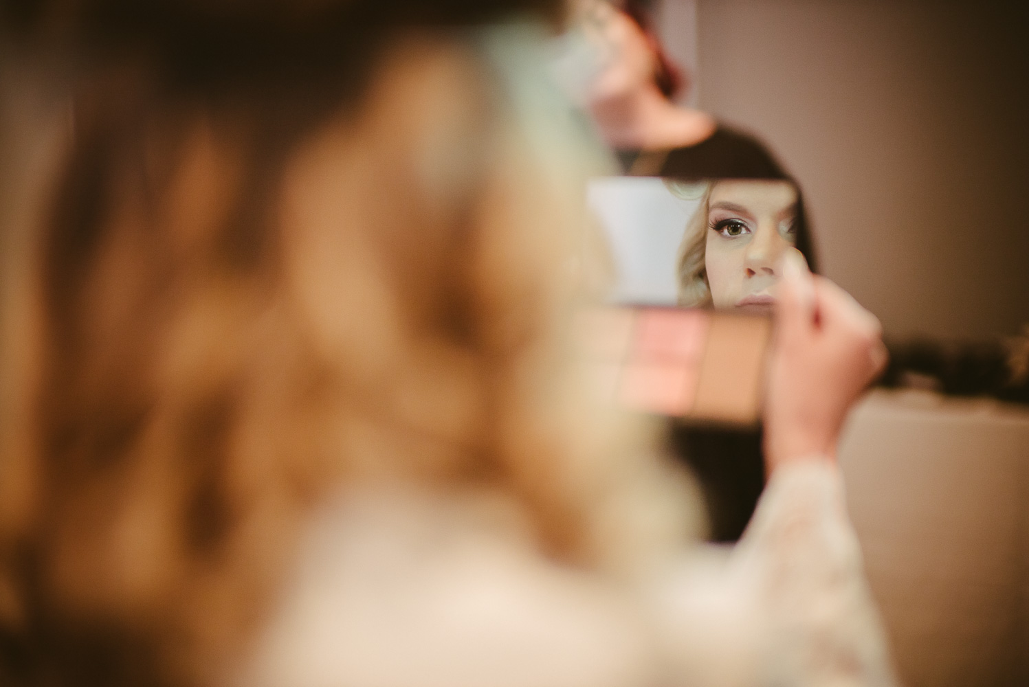 Bride see her reflection in a small makeup mirror St Anthony Hotel Wedding-03