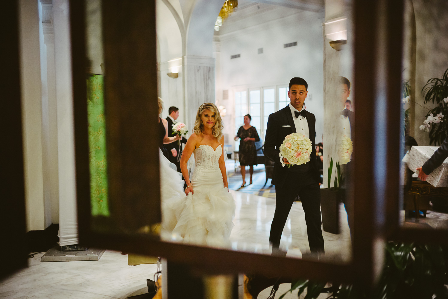 Coupel arrive walking through the hotel lobby captured in the mirror St. Anthony Hotel San Antonio Wedding Reception-32