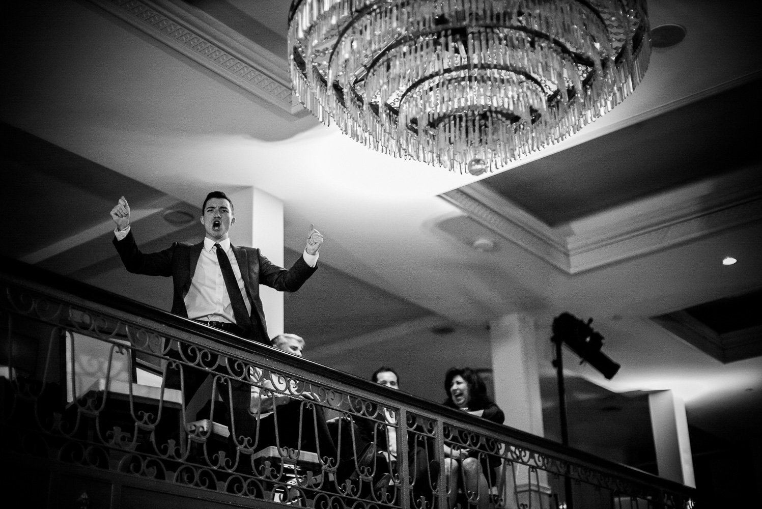 Excited guests raises his arms reacting to guests below dancing St. Anthony Hotel San Antonio Wedding Reception-50
