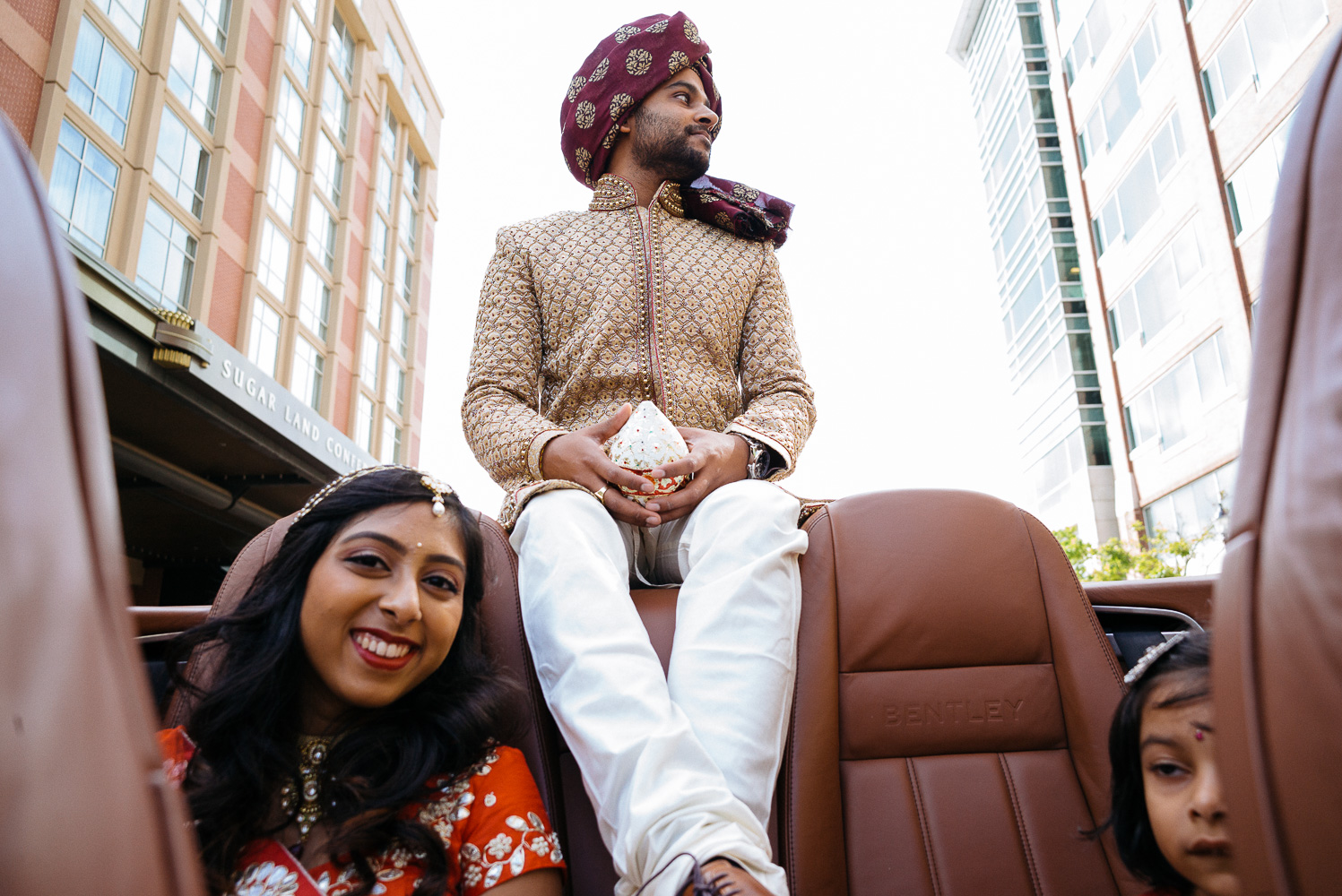 The groom sits on back of the car during the baraat Hindu Jewish fusion wedding Sugar Land Marriott Hotel Texas-028