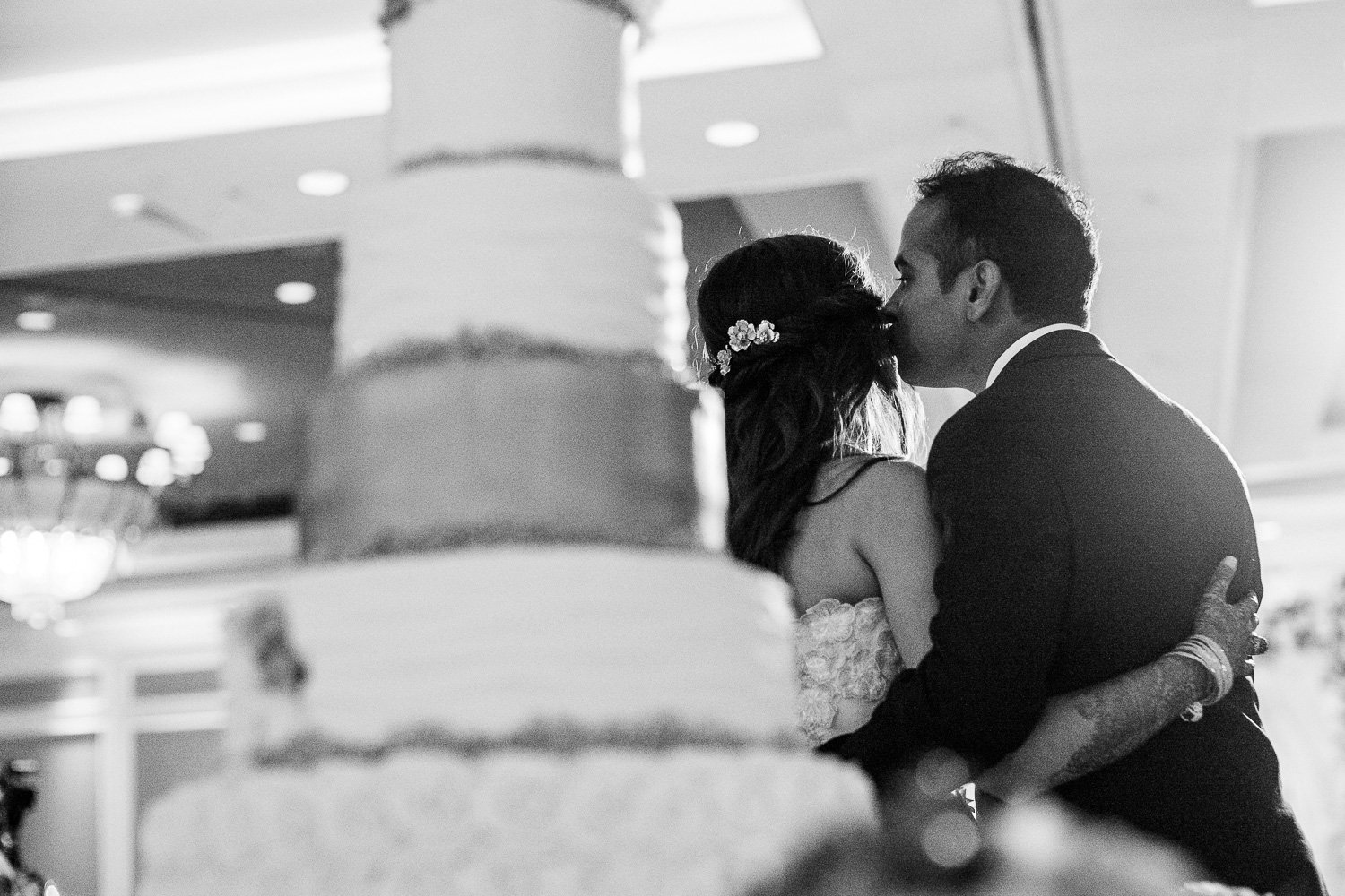 Bride and groom kiss after cutting the cake Hindu Jewish fusion wedding Sugar Land Marriott Hotel Texas-082