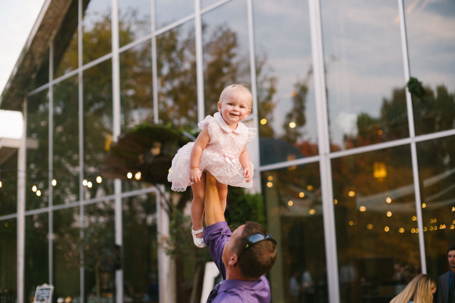 During cocktail party a little girl is hoisted up into the air at Barr Mansion Austin Wedding Photos-Philip Thomas