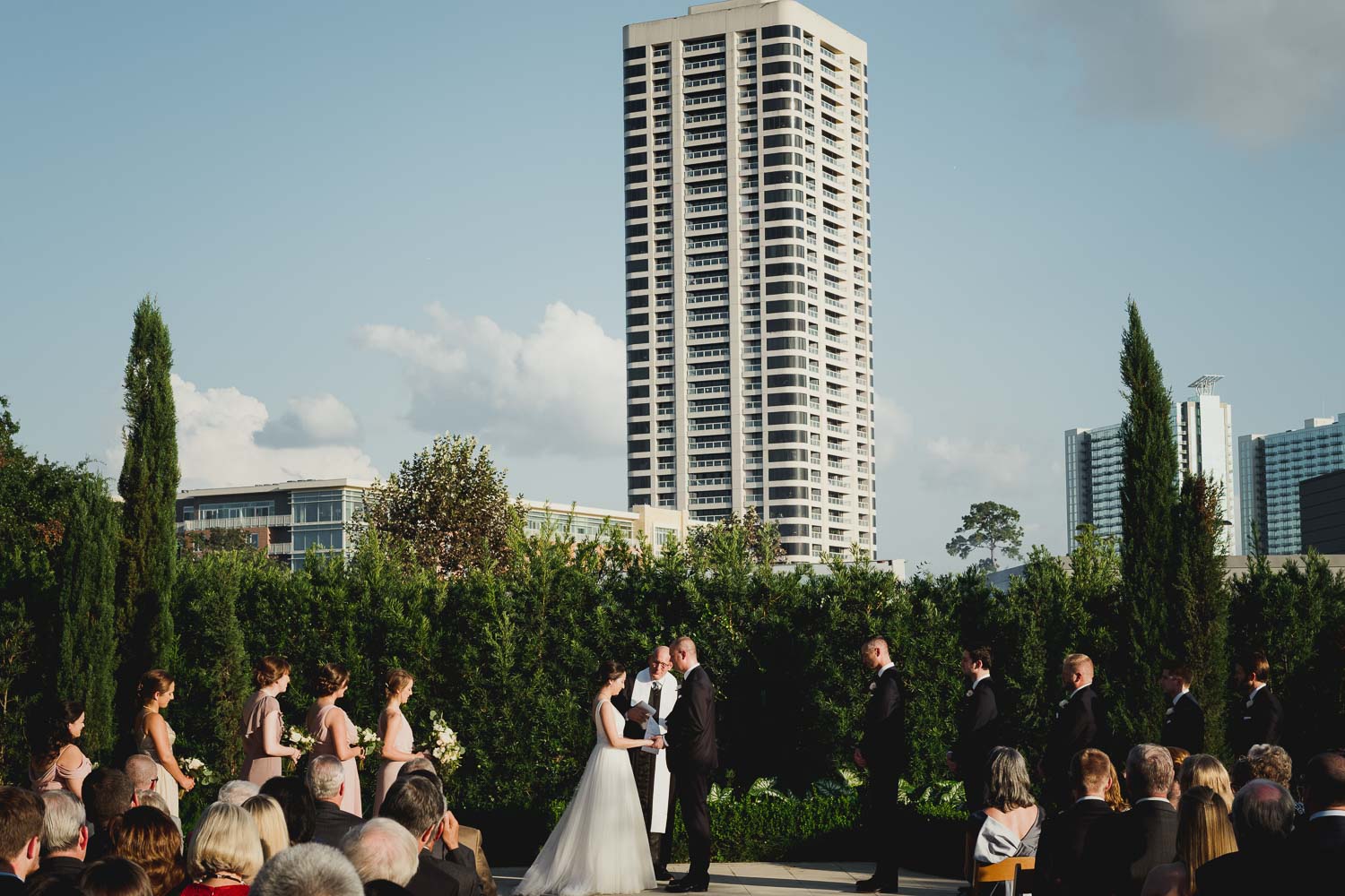Wide shot of wedding ceremony with Houston backdrop Cherie Flores Garden Pavilion Wedding Hermann Park Houston Texas-Philip Thomas