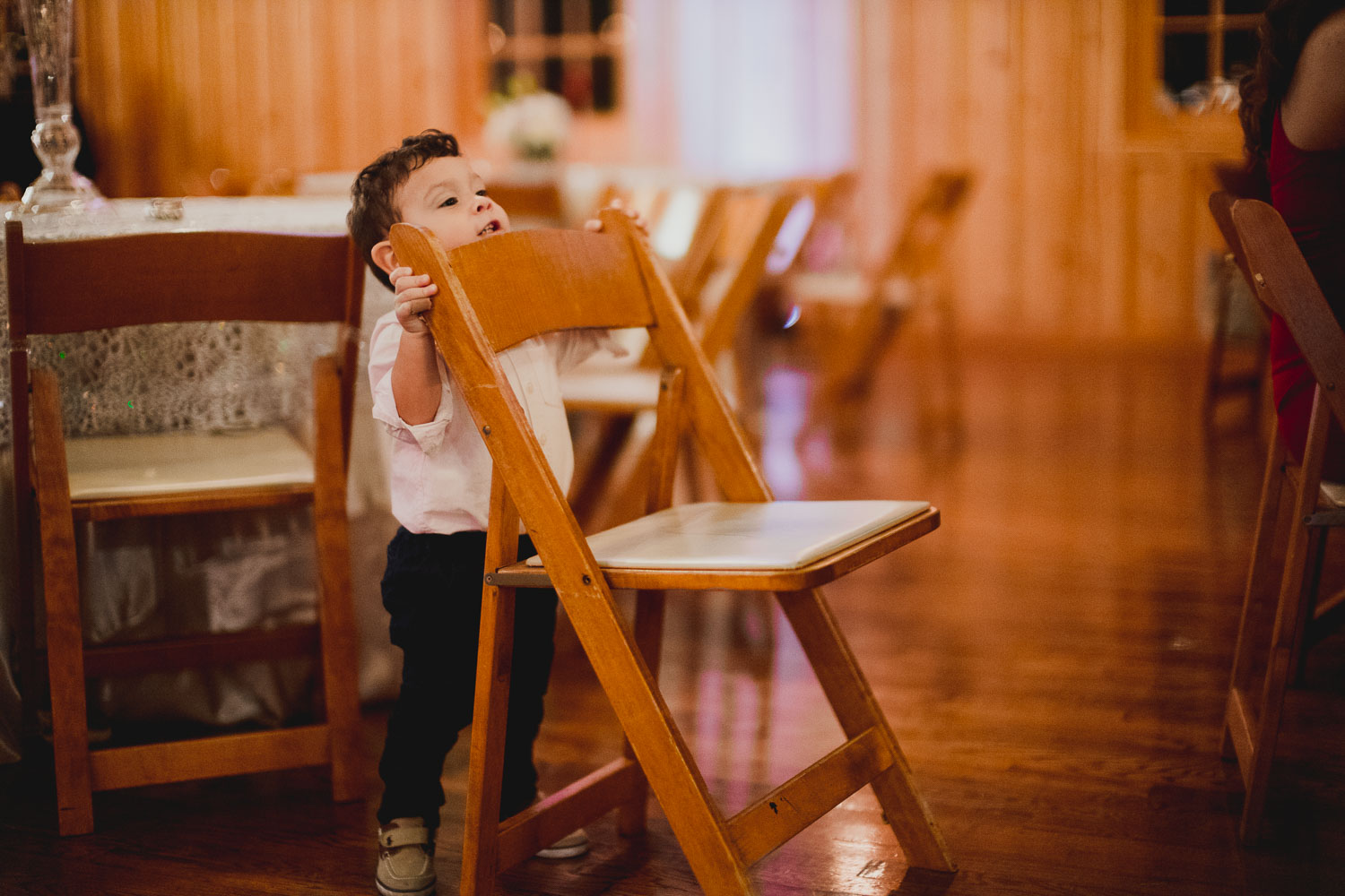 Little boy hides behind chair and a wedding reception The Springs Event Venue Wedding Photos-Philip Thomas