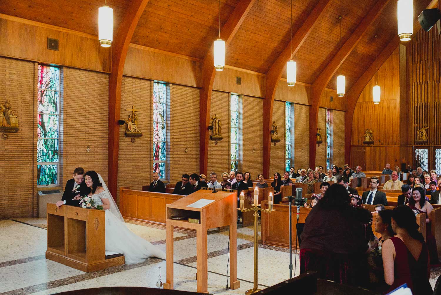 Melody and Alex kneel during wedding ceremony at Immaculate Conception Chapel at Oblate School of Theology -Philip Thomas