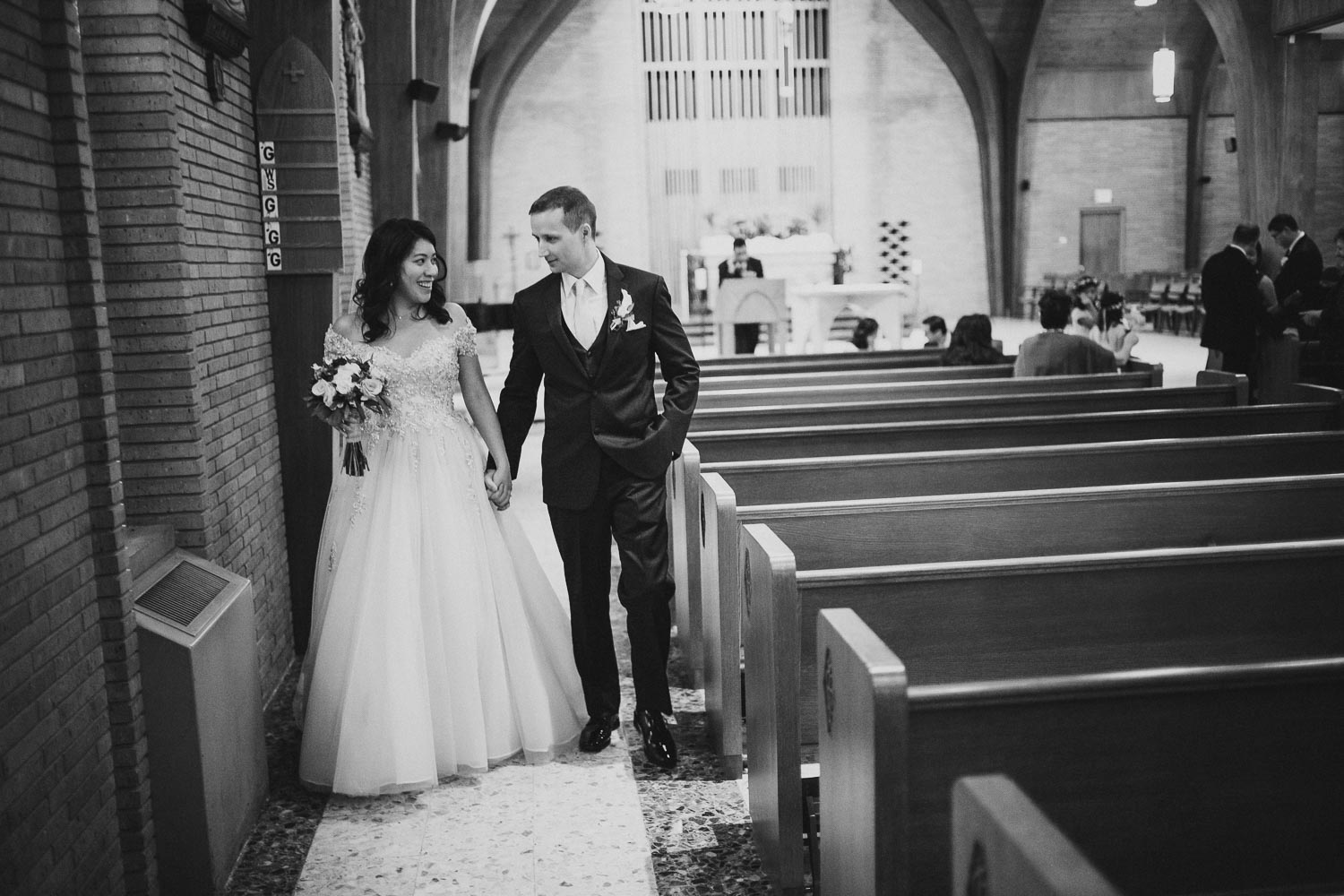 Couple walk down side aisle of church after ceremony at Immaculate Conception Chapel at Oblate School of Theology -Philip Thomas