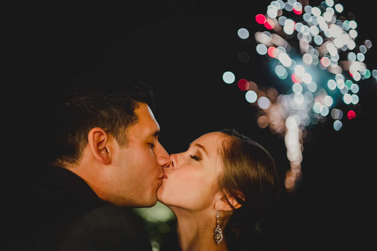 Couple kissing with fireworks in background Paniolo Ranch Wedding Reception-Philip Thomas