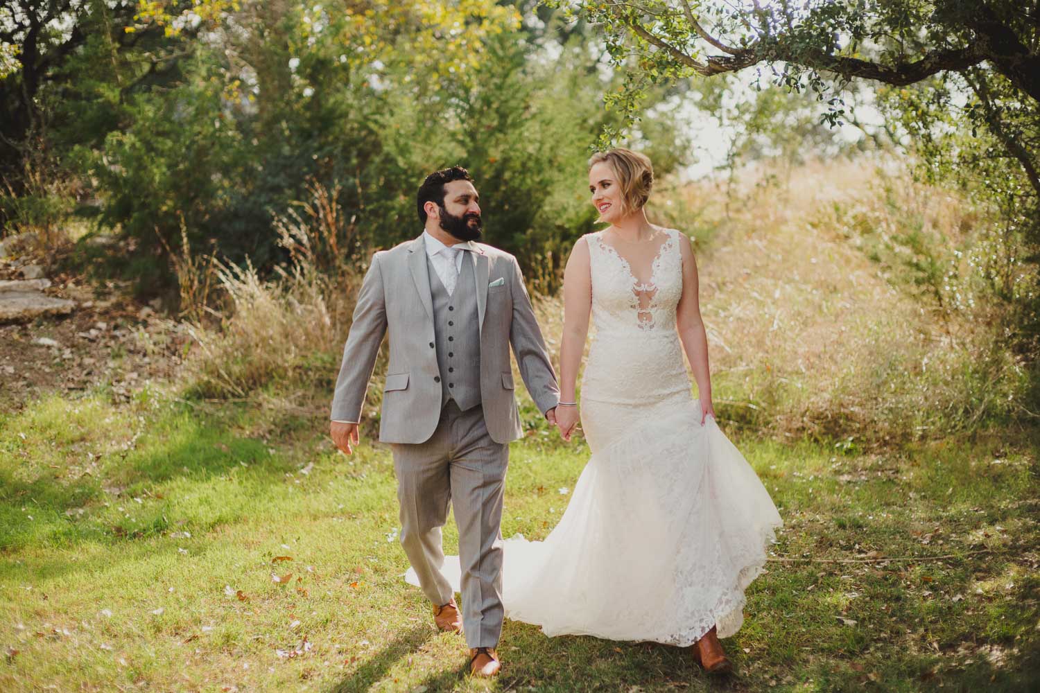 Couple walk down a meadow at RUSTIC BARN WEDDING at VISTA WEST RANCH DRIPPING SPRINGS _ BRANDI + AJ-26