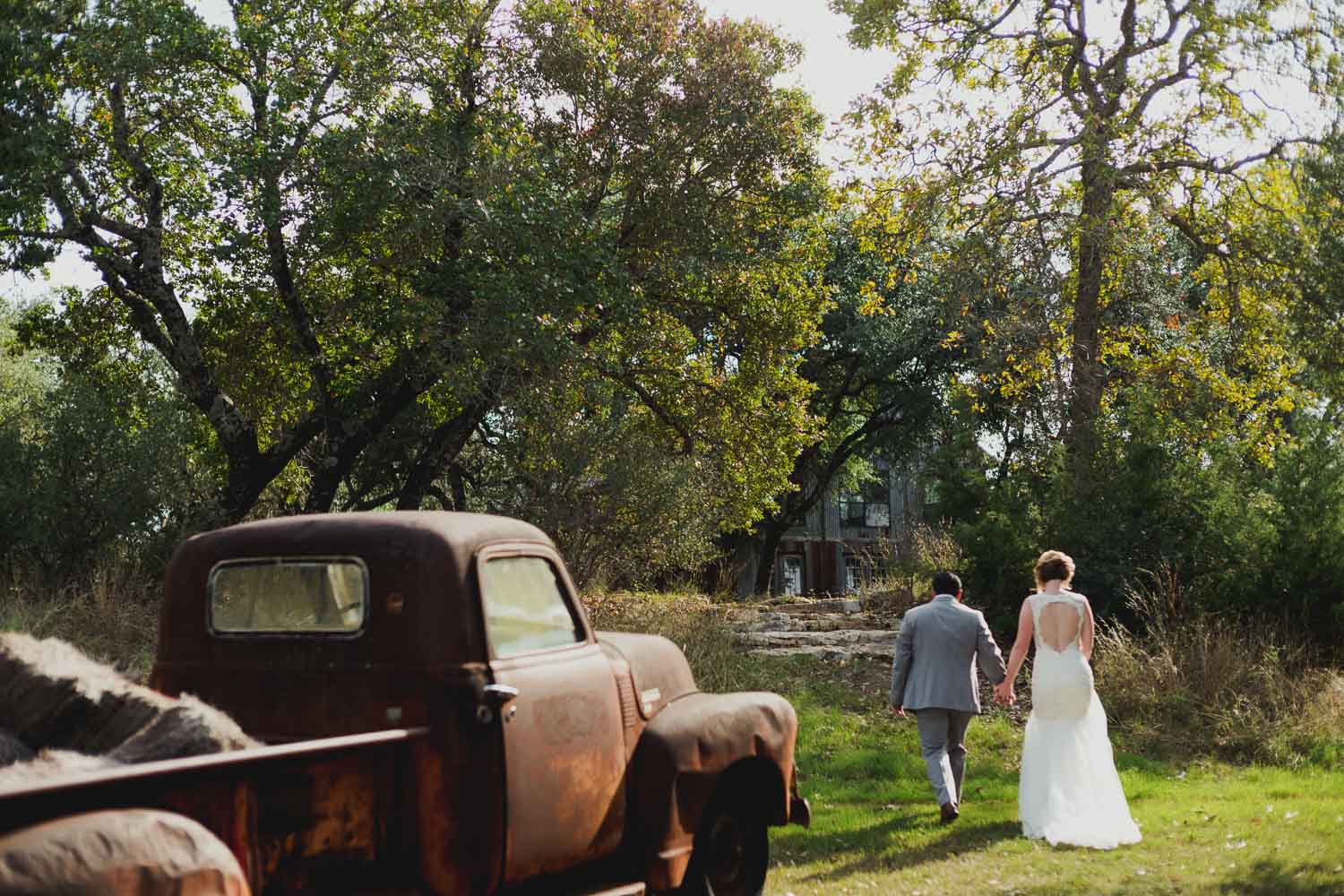 Wedded couple stroll back toward reception at RUSTIC BARN WEDDING at VISTA WEST RANCH DRIPPING SPRINGS _ BRANDI + AJ-28
