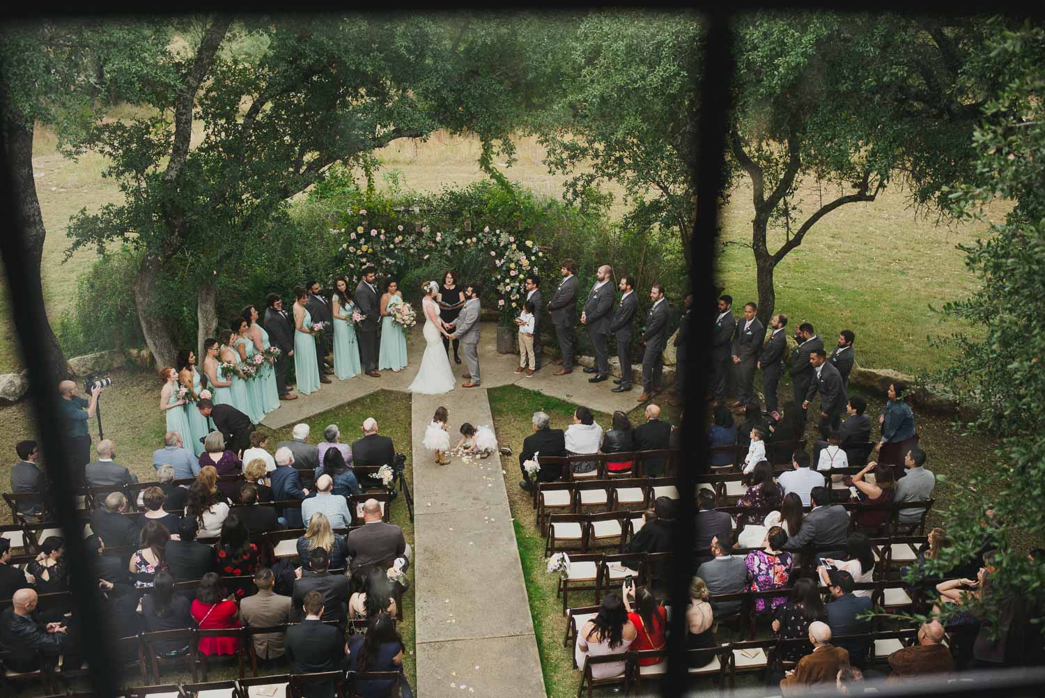 Ceremony shot through window shows flower girls picking up petals during ceremony RUSTIC BARN WEDDING at VISTA WEST RANCH DRIPPING SPRINGS _ BRANDI + AJ-38