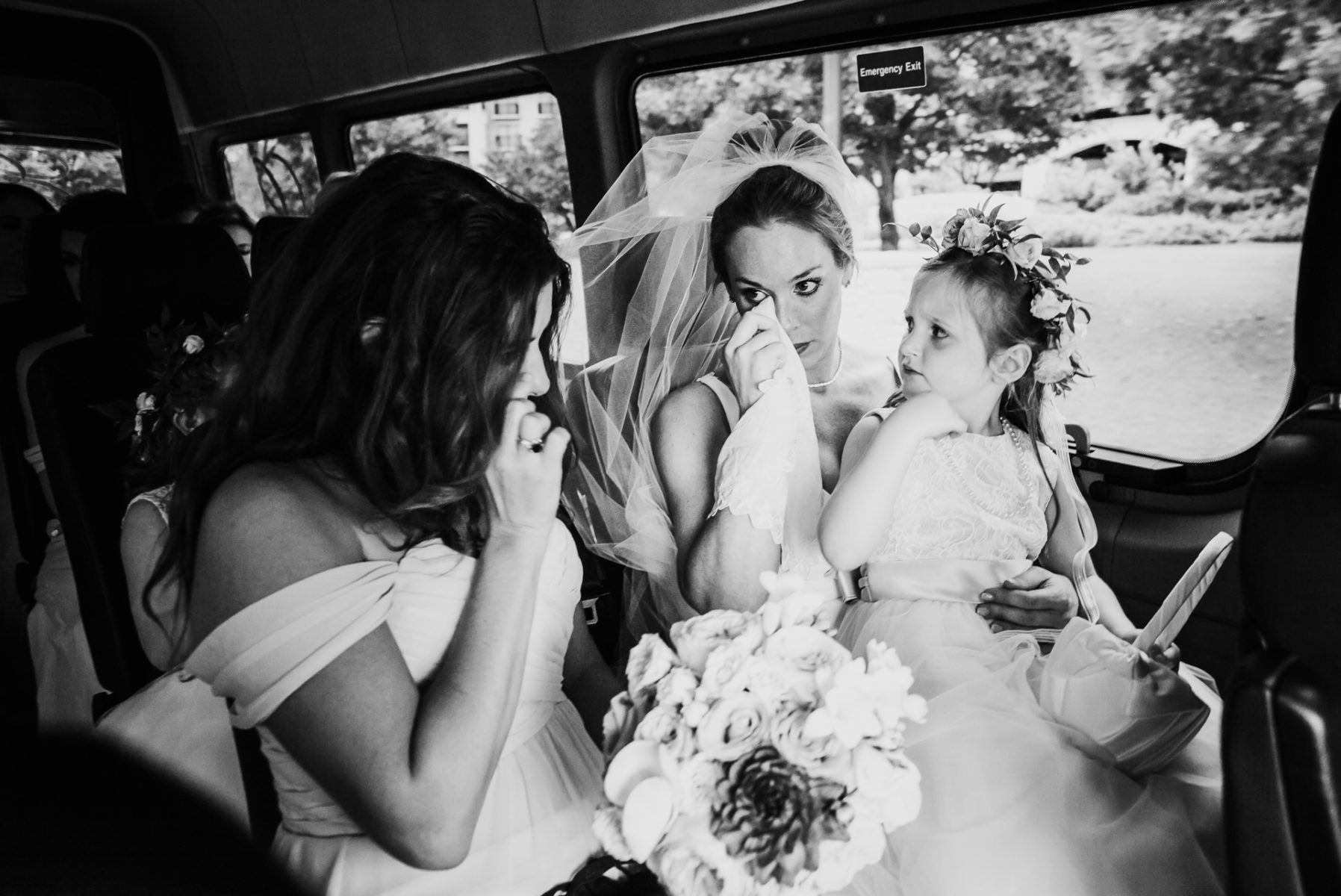 The bride wipes a tear away as she travels in a limo to wedding with flower girls sitting on her lap in San Antonio Texas