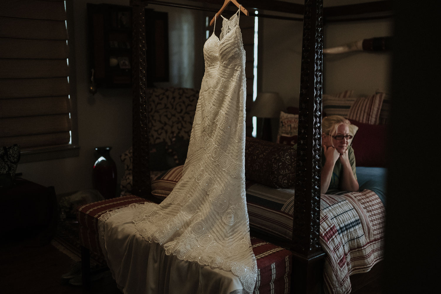 Dress hangs from four poster bed as guest lies on bed