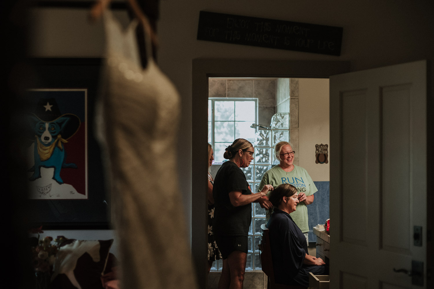 Bride sits in bathroom as hairstylist fixes her hair