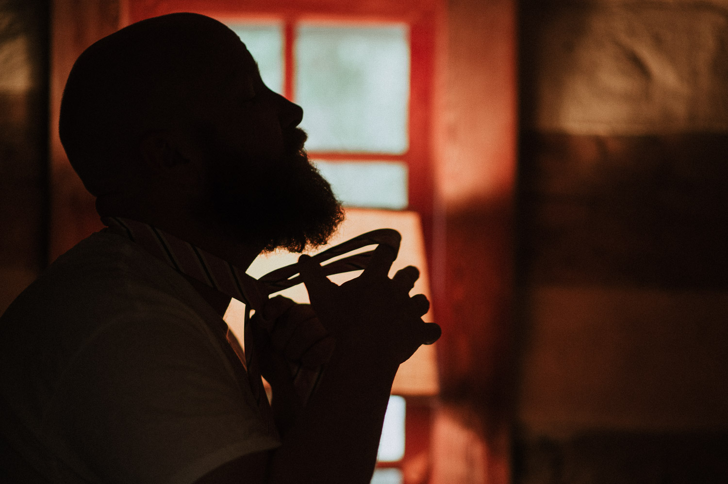 Groom fixes his tie as a silhouette