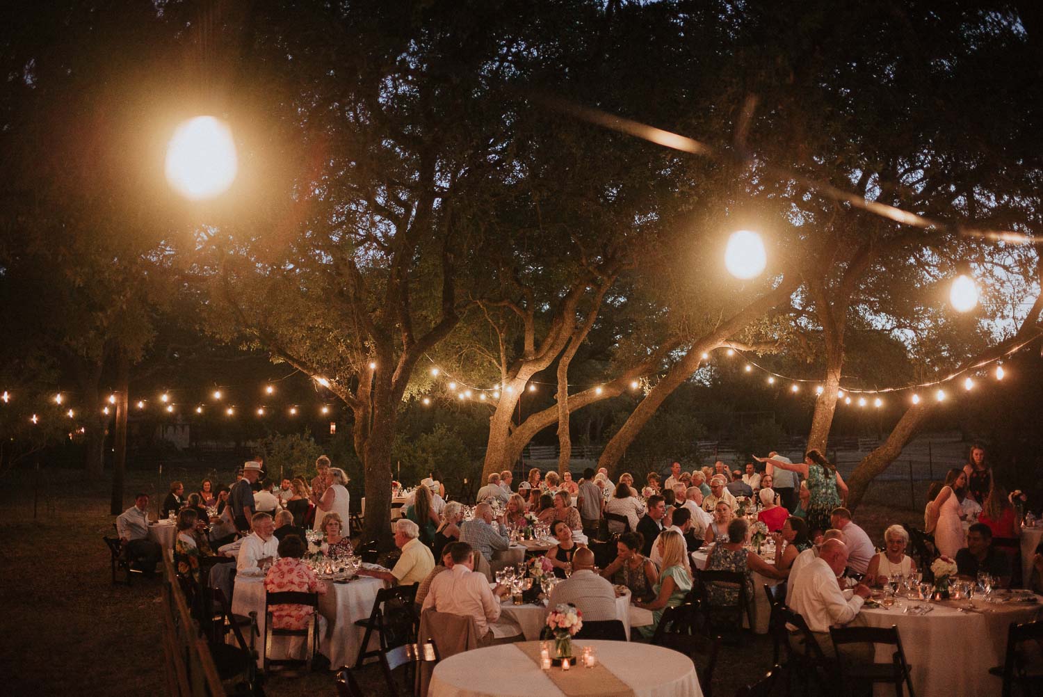 A late night shot under hanging lights shows guest seated during dinner