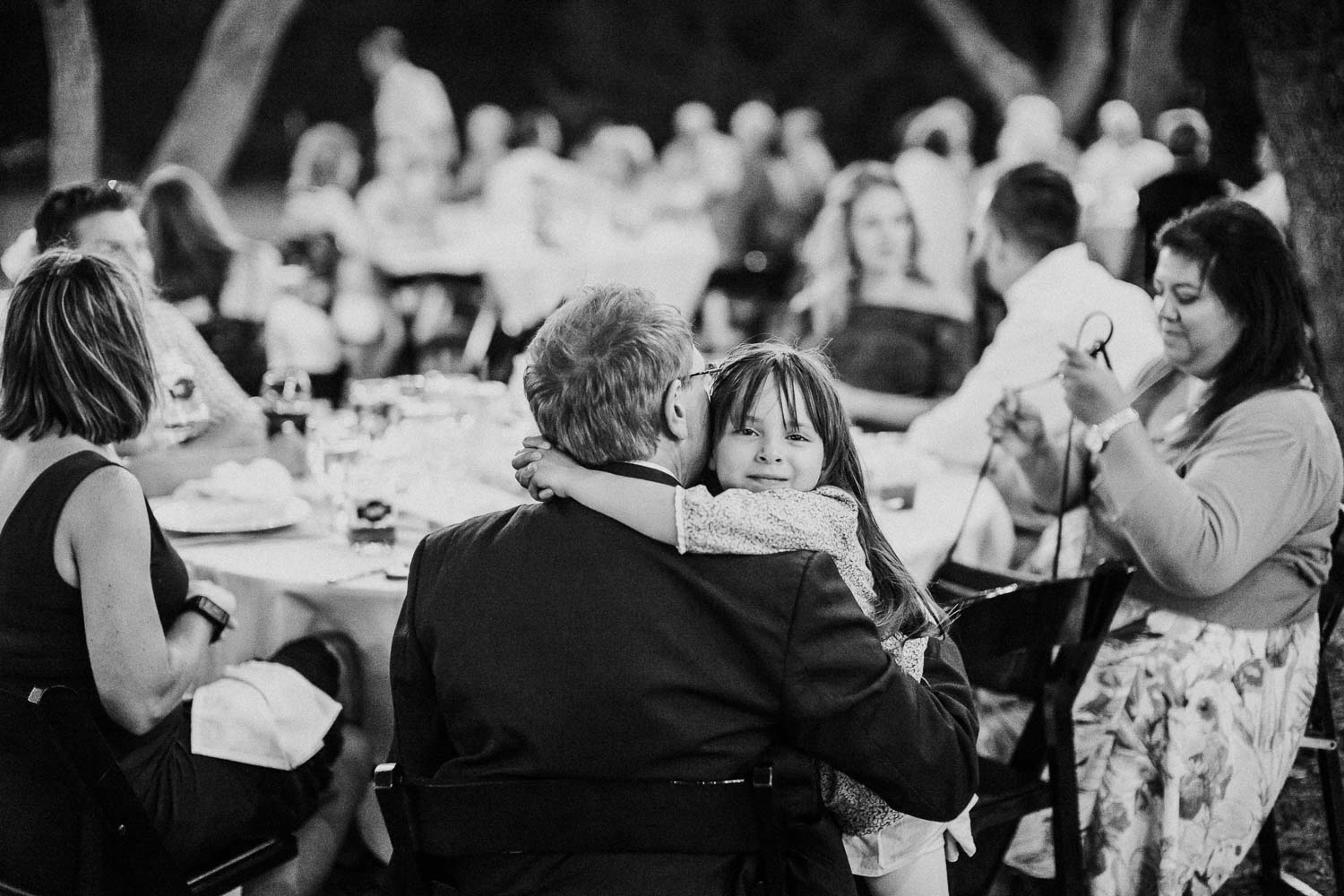 A little girl wraps her arms around a man at a wedding reception in Bulverde, Texas