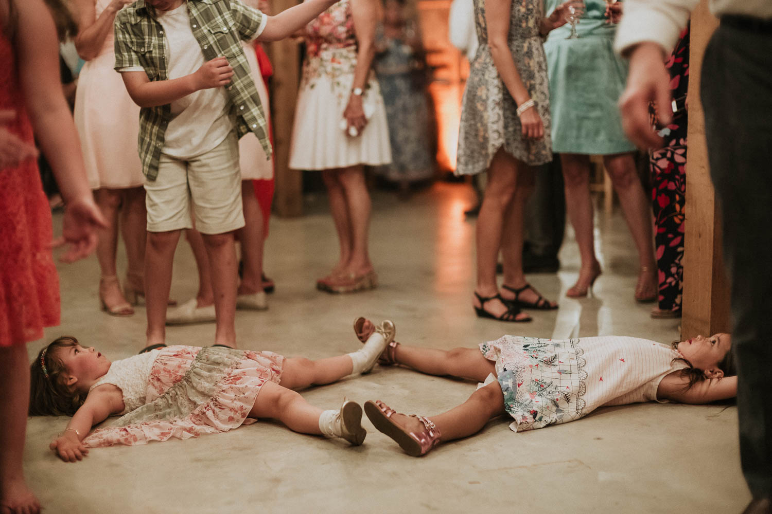 Funny antics between two girls at a wedding reception shows the young girls lying down touch feet