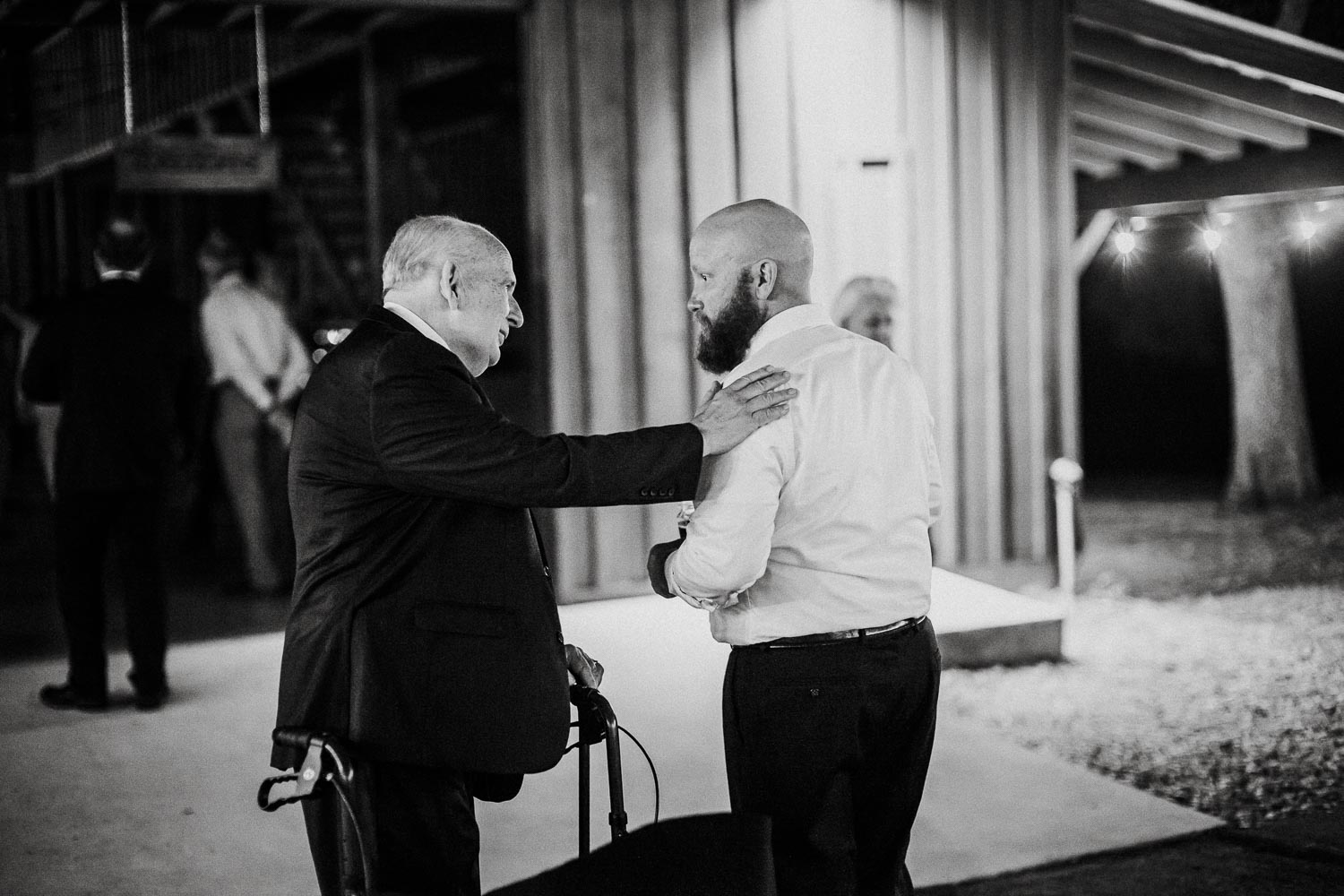 Father of the bride pats the grooms shoulder