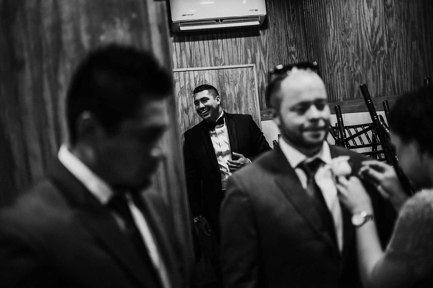 Guys gather around the groom in a restroom McAllen-South-texas-Wedding