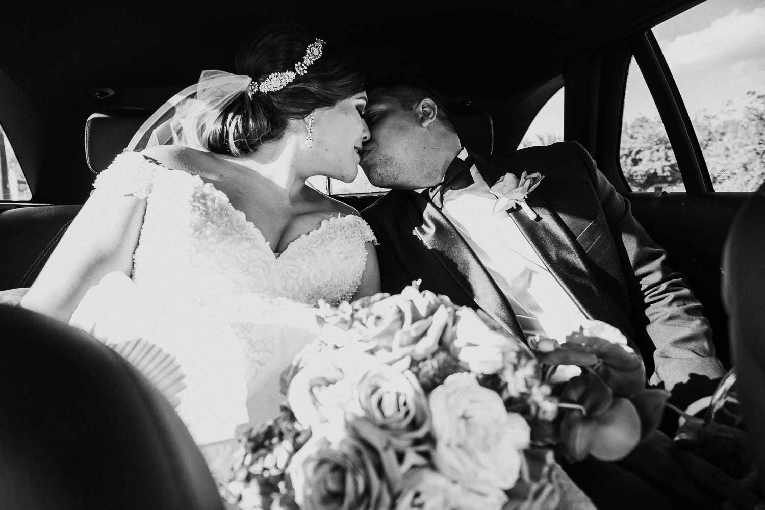 Happy couple kiss in the back of a car enroute to the wedding reception at Villa De Palmer, McAllen