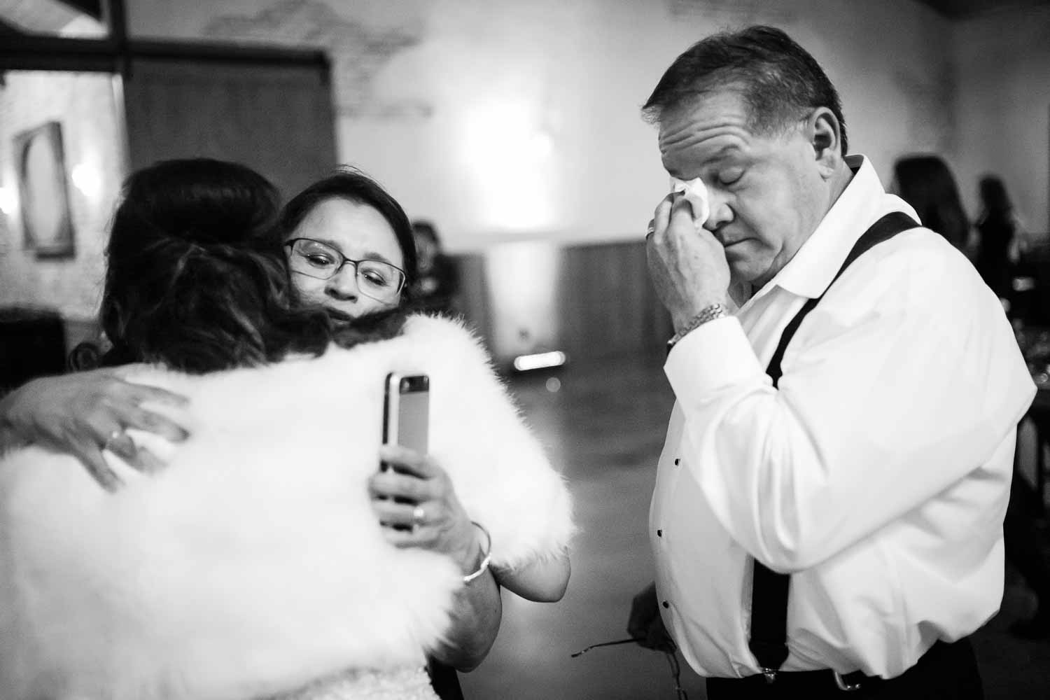 Father wipes away his tears as the brides mother hugs before departing the wedding reception -The Chandelier of Gruene Weding Photos -L1004838-Philip Thomas Photography