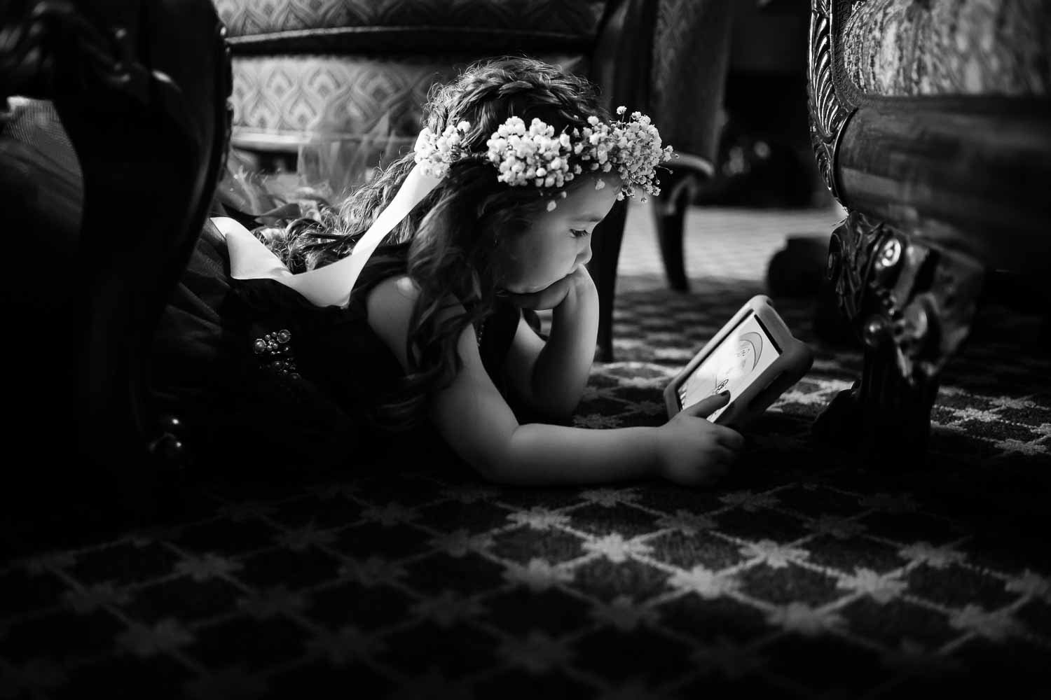 A flower girl dressed up relaxes by watching a movie on a ipad at the Menger Hotel Wedding Ceremony San Antonio Reception Grand BallroomSan Antonio -Leica photographer-Philip Thomas Photography