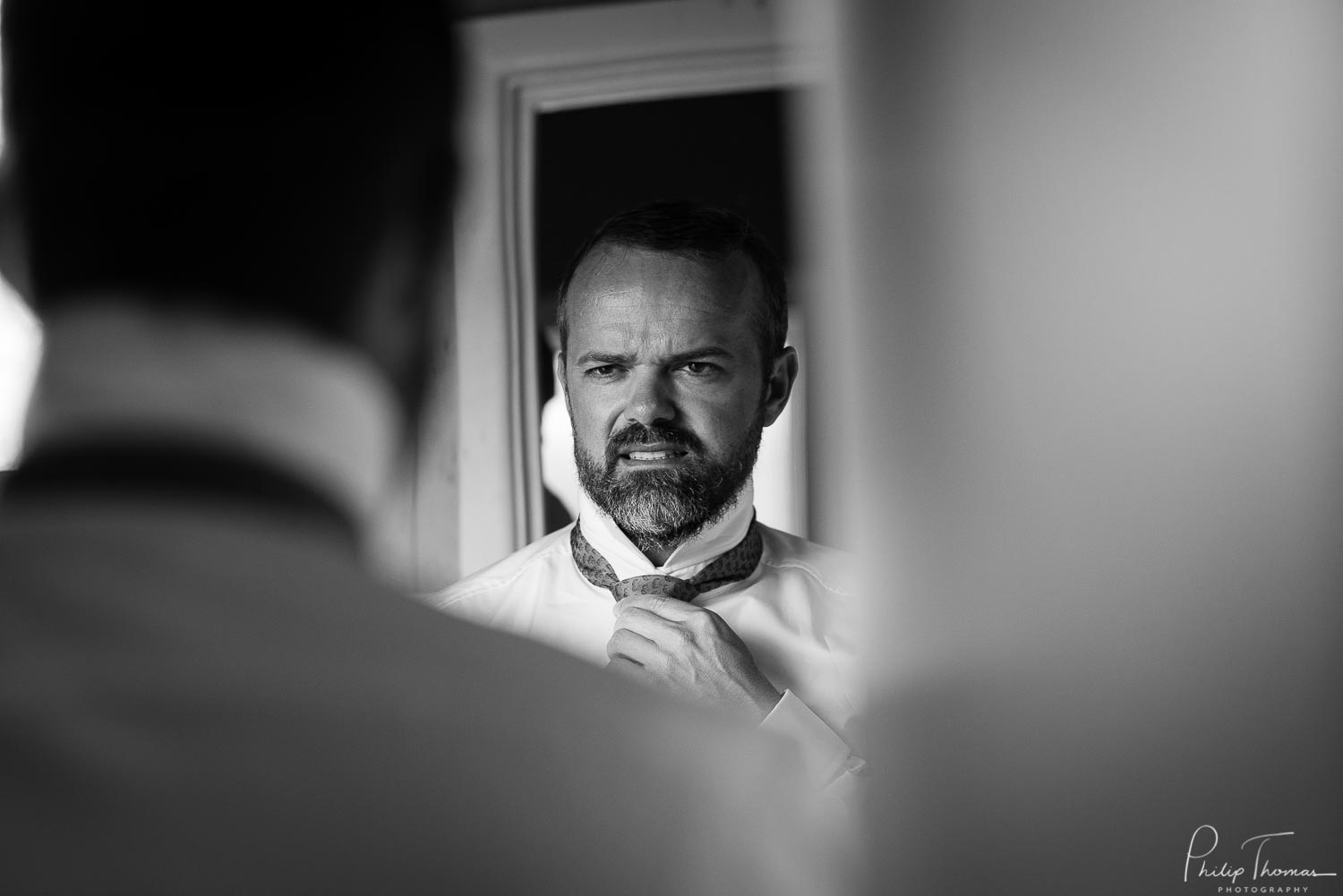 Phillip the groom checks in the mirror on his wedding day