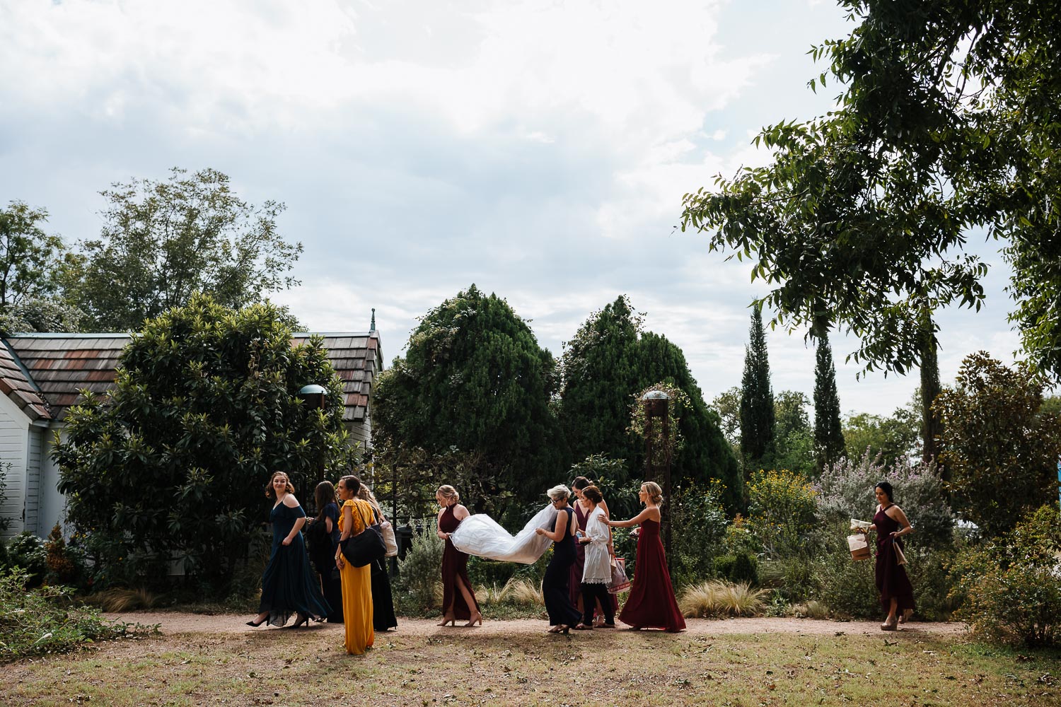 Wide shot of bride and bridesmaids with her dress held out at Barr Mansion, Texas